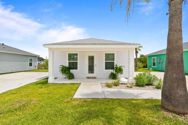 Front view of a modern single-family home in Rockport, Texas, featuring a white exterior, landscaped yard, and a concrete driveway, highlighting the local real estate offerings.