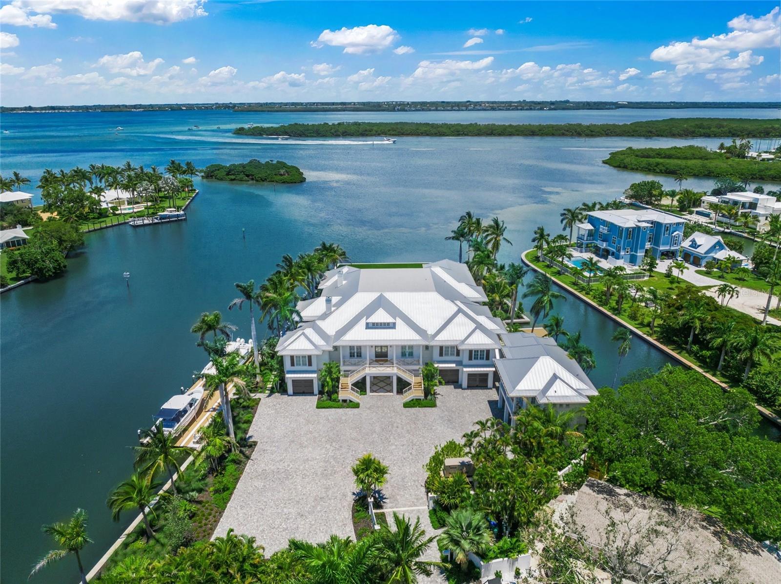 Welcome to your private, gated estate on Longboat Key, where coastal luxury meets effortless sophistication. Boasting over 730 feet of water frontage, this stunning property offers panoramic views of Whitney Bayou and Harris Canal and provides the ultimate waterfront lifestyle. With 9,243 square feet of air-conditioned living space and a total of 21,562 square feet on over an acre of pristine land, this estate is a masterpiece of design and craftsmanship. Designed in the timeless British West Indies style, this home showcases vaulted ceilings, extensive trim detailing, white oak floors throughout, and two fireplaces, creating an ambiance of elegance and warmth.The expansive covered patios and porches invite you to embrace the serenity of waterfront living, while the heated pool and an impressive 13' x 13' hot tub serve as the ultimate retreats. A custom outdoor fire pit, two outdoor kitchens, and indoor and outdoor pool tables elevate the entertainment experience.For boating enthusiasts, this estate is unrivaled, featuring four low-profile boat lifts—the largest accommodating vessels up to 30,000 pounds, the second suitable for a vessel up to 20,000 pounds, and the third and fourth lifts each with a 5,000-pound capacity, ideal for jet skis, kayaks, and paddle boards. Located just 10 minutes from the Gulf of Mexico by boat and 5 minutes to Shore and Mar Vista restaurants, this is the perfect haven for life on the water.Inside, the Wolf Sub-Zero appliances provide top-tier performance in a gourmet kitchen built for culinary excellence. A Control4 smart home system offers seamless automation throughout, while HVAC-equipped garages ensure comfort year-round. The multiple garages can accommodate up to 9 cars, and the massive driveway can host 20+ vehicles.The residence boasts six spacious bedrooms, each with an en-suite bathroom, plus an additional full bath and two half baths. Designed for both productivity and leisure, the home features his and hers offices, a media/theater room, a fully equipped gym, sauna, golf simulator, tackle garage, and a workshop.A private guest suite with a separate entrance includes a kitchenette, dining room, living room, bedroom, and bathroom, offering a luxurious retreat for visitors. With two state-of-the-art elevators, expansive landscaping, and a maintenance-free turf yard, this estate blends modern convenience with natural beauty.Ideally located near pristine beaches, world-class shopping, and gourmet dining, this estate is the epitome of waterfront elegance and exclusivity. Experience the pinnacle of coastal living—this is truly paradise found.