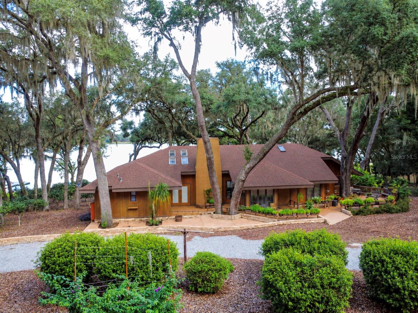Welcome to an extraordinary lakefront retreat where space, character, and spectacular water views come together on beautiful Lake Rosa in Melrose, Florida. This one-of-a-kind property offers not just one exceptional home, but two residences, creating an incredible opportunity for a large family, multigenerational living, guests, or those looking for a private lakefront getaway with additional space on an expansive 9.2 acres. The magnificent main residence offers an impressive 5,187 square feet of heated and cooled living space, featuring 4 bedrooms and 4 1/2 bathrooms. From the moment you drive onto the property, you will feel you have entered a park with the beautifully manicured grounds, which include 1000 planted, mature camellias. Once inside the main house you will take in vaulted ceilings and the expansive and breathtaking lake views that set the tone for relaxed lakefront living. You'll find wonderful spaces designed for both entertaining and everyday enjoyment, including two loft areas, a cozy fireplace, wet bar, and a wine cellar—perfect for evenings spent with friends and family after a day on the lake. The generous living spaces provide plenty of room to spread out while still maintaining the warm, inviting feel you'd expect from a true lake home. The outside decks from this home give over 3000 sq ft of additional space to enjoy the outdoors from many rooms and levels of the home. And then there's the second residence, offering an additional 2,496 square feet of heated and cooled living space, with 2 bedrooms and 1 bathroom. Complete with its own deck overlooking the lake, this separate home is ideal for guests, extended family, a caretaker, or anyone who wants their own private space while still being just steps from all the lakefront fun. With a combined 7,683 square feet of heated and cooled living space and 6 total bedrooms, this is far more than a home—it's a lakefront lifestyle and an opportunity that's hard to duplicate. Imagine morning coffee with the lake as your backdrop, afternoons enjoying the water from your private dock and evenings gathered around the fireplace or relaxing on the deck as the day winds down. Whether you're looking for a spectacular full-time residence, a weekend escape, or a property designed for entertaining generations of family and friends, this one delivers the space, setting, and character to make lake memories for years to come. Come experience the magic of Lake Rosa for yourself—this is lake living with room for everyone!