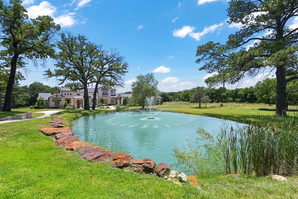 Stunning multigenerational estate on 6.29 private acres blends luxury craftsmanship with resort-style living. The open-concept main hall seamlessly connects the kitchen, living, dining, and breakfast areas. This fully equipped dream kitchen includes Thermador appliances, dual farmhouse sinks, dual dishwashers, and built-in Miele coffee system. The main residence features 4 bedrooms with ensuite baths, including a spacious primary suite with separate his-and-hers closets, laundry, folding station, and vanity. Just off the foyer, a serene study with cathedral ceiling opens to its own paver courtyard with cafe lighting. Designed for exceptional indoor-outdoor entertaining, this home features a front paver courtyard with fireplace, front and rear balconies, a large covered patio equipped with drop screens, accordion style glass doors, an outdoor kitchen, and multiple fire features. The main level game-media room offers direct pool and patio access and includes a wet bar and beverage station, while the heated pool and spa complete the unmatched outdoor living experience. Interior finishes include expansive kitchen island, solid 8” white oak hand scraped hardwood flooring throughout main areas, and tile in wet areas. Additional highlights include whole-home audio, LED lighting throughout, hard-wired security cameras, water purification system, and four tankless water heaters. The guest house main level includes living area, full kitchen, full bath, while the second level features a spacious bedroom with laundry—ideal for extended stays or multigenerational living. The property includes two ponds with a water feature in front, a well-fed irrigation system, and a mix of cleared and wooded land. Car collectors will appreciate the 6 garage bays with climate control and one pass-through door.