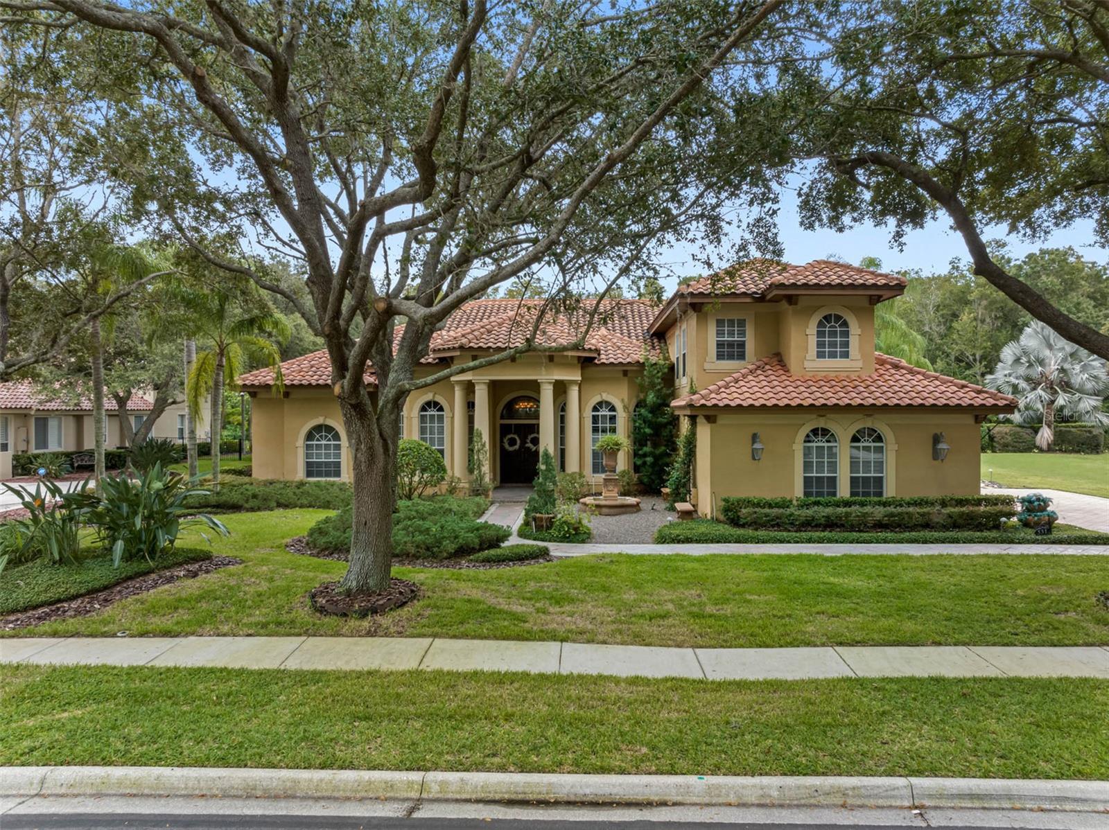 Priced to SELL! Designer Mediterranean Custom Estate in the Prestigious Wentworth Community Welcome to this exquisite custom-built Mediterranean home, ideally situated in a serene cul-de-sac beneath stately oak trees within the famed Wentworth Community—one of Tarpon Springs' most coveted manned-gated neighborhoods. From the moment you arrive, elegance and craftsmanship define every aspect of this home. A custom double walnut front door opens into a grand foyer, setting the tone for the luxurious finishes that continue throughout the residence. To the right of the foyer, you'll find an expansive formal dining room accompanied by a custom-designed wine room, capable of storing over 350 bottles and featuring a built-in humidor—perfect for the discerning collector. The gourmet kitchen is a chef’s dream, showcasing 42” cabinetry, top-of-the-line Monogram appliances, a large central island, and a cozy eat-in area—ideal for casual family meals or entertaining guests. The owner’s suite is a private retreat, complete with a sitting area and a custom-designed craftsman closet—a standout feature in both form and function. The executive office offers sophistication and productivity, featuring custom cabinetry and shelving. Upstairs, you'll discover a spacious guest suite or game room—the fifth bedroom—equipped with beautifully crafted built-in wooden cabinetry. Additional upscale features include plantation shutters, integrated surround sound, and meticulous attention to detail throughout. Step outside to your screened brick paver lanai, a true oasis with a peaceful conservation area. Enjoy year-round outdoor living with a outdoor kitchen, saltwater pool and spa, and generous covered seating areas. Just beyond the lanai, indulge in evenings by the stone fireplace, gather around the fire pit, or relax under the pergola surrounded by tranquil fountains. This home is a rare opportunity to enjoy luxury living in one of the area’s most exclusive communities—combining elegant design, functional spaces, and stunning outdoor amenities. Please note that the golf course is no longer operational.