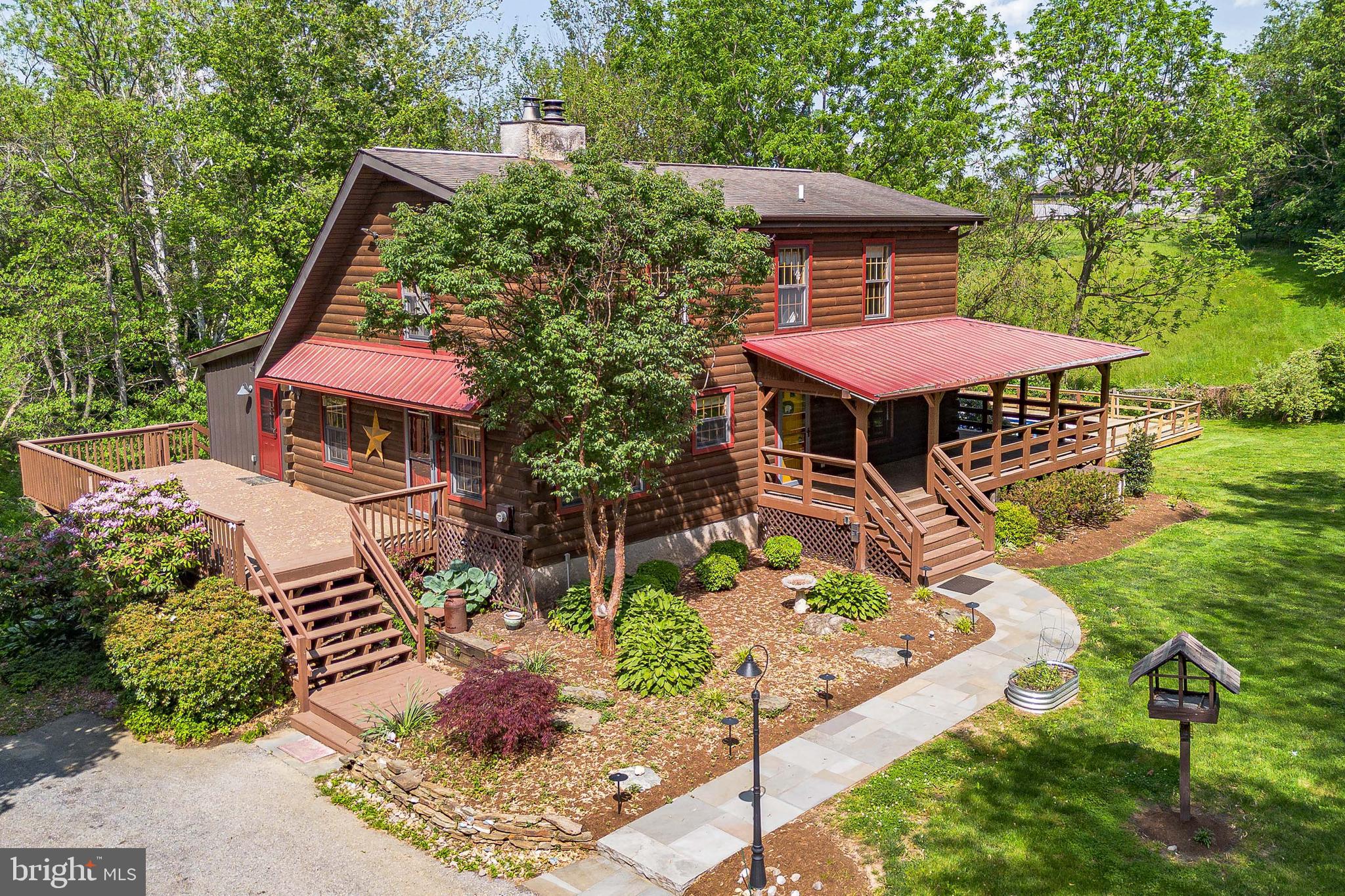 Welcome to 1821 W Strasburg Road, a 4-bedroom, 3-full, 2-half bath log cabin-style single-family home in West Chester. Set back from the road and surrounded by mature trees, this almost 3 acre property offers exceptional privacy along with a spacious driveway. Inside, the foyer features a ceiling light and detailed chair rail with wainscoting. A powder room is conveniently located just off the entry. To the left, the kitchen showcases hardwood floors, exposed ceiling beams, a wood and wainscoting backsplash, granite countertops, and stainless steel appliances. The kitchen flows into the dining room, which includes hardwood flooring, a farmhouse-style chandelier, chair rail with wainscoting, exposed beams, and access to the wood deck. The living room offers a warm and inviting setting with hardwood floors, a partially vaulted ceiling, a wood-burning fireplace, two ceiling fans, and built-in bookcases. The main level also includes a spacious primary suite featuring hardwood floors, a two-story semi-vaulted ceiling, exposed beams, a ceiling fan, and a large walk-in closet. The en-suite bathroom includes a double sink vanity with wood countertops, a step-in shower with seating, and a linen closet. An in-law suite on the main level adds flexibility and privacy, with its own entrance from the living room. This space includes an eat-in kitchen with engineered hardwood flooring, quartz countertops, tile backsplash, and access to the deck. The suite also features a bedroom with a semi-vaulted ceiling and ceiling fan, along with a full bathroom that includes a tub and shower combination. Upstairs, a balcony overlooks the living room below. This level includes two additional bedrooms, one with exposed beams and the other with a semi-vaulted ceiling and ceiling fan, along with a full bathroom featuring tile flooring, a double sink vanity, and a tub and shower combination. The finished lower level expands the living space with a family room featuring engineered hardwood flooring, a ceiling fan, a dry bar with a wood countertop, and built-in desk areas. A bonus room with sliding door access to the exterior offers additional flexibility for a home office, gym, or guest space. The lower level also includes a laundry room with built-in cabinetry, a utility room with a workbench and water softener system, a second powder room and additional closets. The outdoor space is a true highlight of this home, featuring a brand new pool and surrounding decking installed in 2025, along with additional decking that wraps around the home for multiple areas to relax and entertain. A koi pond and dedicated outdoor seating area create a peaceful setting, while a built-in electric dog fence adds convenience for pet owners. To top it off, the property benefits from exceptionally low taxes. Located in a private setting with easy access to parks, green space, and the amenities of West Chester, including shopping, dining, and major routes, this home offers a unique blend of character, space, and convenience. Don’t miss the opportunity to make 1821 W Strasburg Road your own.