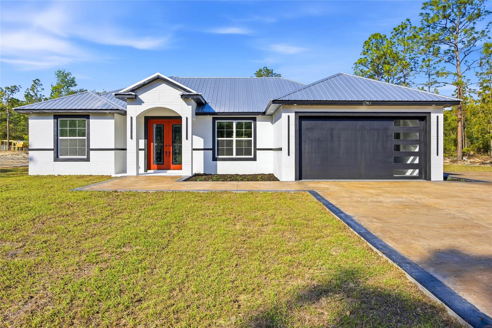 Welcome to this exceptional 4-bedroom, 3-bath custom home tucked away in a peaceful corner of Dunnellon, offering over 2,700 total square feet, 2,011 living square feet, and set on an impressive 1.16-acre lot. From the moment you arrive, this home makes a powerful first impression with its striking curb appeal, bold double-door entry, metal roof, upgraded modern-style garage door, and painted and stamped concrete driveway that immediately sets it apart.Inside, the quality and intentional design are impossible to miss. The home features upgraded tile flooring throughout, elegant architectural details, and a spacious split floor plan designed for both everyday comfort and elevated living. The main living area is a true showstopper, centered around stunning charcoal painted ornate coffered ceilings that create dramatic contrast, depth, and character. A sleek electric fireplace with custom built-in accents completes the space with a polished, modern feel.The kitchen is nothing short of spectacular, designed with beauty and practicality in perfect balance. You’ll find abundant cabinetry, a large island, gorgeous granite countertops, hidden outlets beneath the cabinetry, and pop-up outlets in the island that preserve the clean lines of the space. The room is elevated even further by a tiered ceiling with changeable ambient lighting, creating a luxurious atmosphere day or night. The kitchen also features glass upper cabinet doors with interior lighting, adding warmth, elegance, and ambiance. A stacked built-in microwave and oven, separate cooktop, pot filler, and a bold charcoal ornate vent hood surround bring together custom functionality and striking design, perfectly echoing the style of the coffered ceilings and giving the kitchen a rich, high-end presence.The thoughtful upgrades continue into the laundry room, where you’ll find the same beautiful cabinetry and granite-style finishes carried through from the kitchen, along with a utility sink that adds convenience without sacrificing style. Even the garage has been elevated with a modern upgraded door and epoxy-coated floors, giving the space a clean, finished look.The primary suite carries the same level of care and luxury, featuring an upgraded walk-in closet designed for both beauty and practicality and a spa-inspired bath with a beautiful double vanity and an EPLO smart toilet, offering comfort, innovation, and a touch of luxury in a space often overlooked.Beyond the walls of the home, the setting offers the best of both worlds far enough away to feel separated from the world, yet close enough to enjoy everyday convenience. Located just a short drive from Rainbow Springs, World Equestrian Center, grocery stores, shopping, and dining, this property blends privacy, style, and accessibility in a way that is hard to find.This is more than a home, it is a true showpiece. Schedule your private tour today.