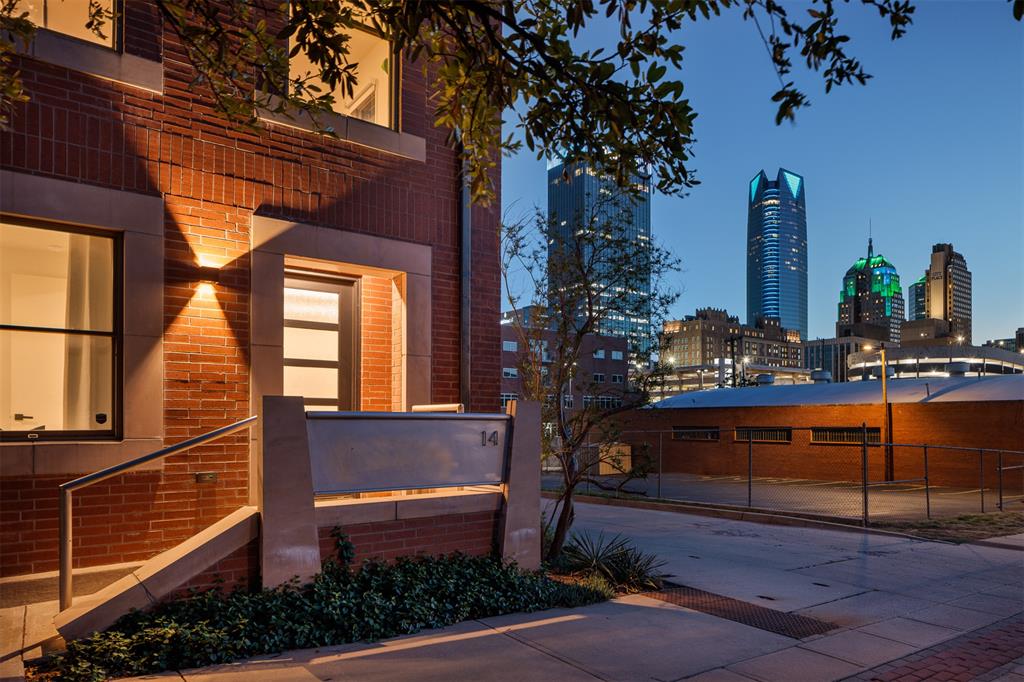 This is what downtown living is meant to be: views, lock-and-leave ease, and a city ready to enjoy. In the heart of Deep Deuce, this end-unit condo makes the downtown Oklahoma City skyline part of the west-facing living space. You’re immersed in the skyline, with icons of our city just outside your windows—Devon Tower, First National Center, City Place Tower, Bank First Tower, and the Skirvin—all visible from the living room and kitchen, and from the balcony. The two-story layout places the main living spaces upstairs, where the views and natural light are at their best. The primary suite, kitchen, living area, powder bath, and balcony are all on one level, creating a natural flow. The balcony is a true extension of the home—expansive and designed for lounging and dining, with access from the living room and primary suite. The kitchen features black Dekton countertops, Bosch appliances, and European-style cabinetry, complemented by white oak floors and clean-lined interiors. Downstairs, a private guest suite with its own bath works well as a guest space, home office, or second living area, along with a foyer and private attached two-car garage. Completed in 2020 as the final residence in the community, the home was built with lasting quality in mind and includes Pella windows and doors, a variable-speed heat pump system, LED lighting with Lutron controls, and a fire sprinkler system. The HOA provides a true lock-and-leave experience, handling landscaping, snow and ice care, and seasonal lighting. Maywood is a beautifully designed community, and NE 3rd Street manages to feel both residential and urban—tree-lined sidewalks and a calm, neighborly feel, all while sitting steps from the best of downtown. Walkable to fine and casual dining in Deep Deuce, and moments from Paycom Center, Bricktown, Scissortail Park, Midtown, Auto Alley and the Oklahoma City Arts District. Whether it’s a full-time home or your urban OKC retreat, it’s an exceptional place to make your own.