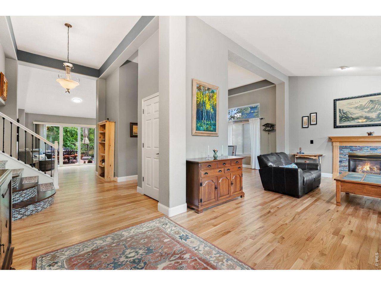 Pride of ownership radiates throughout this beautifully maintained and thoughtfully updated home. The exterior impresses immediately with brand-new insulated custom garage doors and a xeriscaped front yard filled with native Colorado plants. Inside, soaring ceilings and newly refinished blonde hardwood floors create a bright, sophisticated ambiance, complemented by tall baseboards and a modern paint palette. The main level flows seamlessly between the living room with one of two gas fireplaces, the formal dining room, and the kitchen with a sunny breakfast nook. The chef's kitchen features high-end stainless-steel appliances, an induction cooktop with hood, granite countertops, tiled backsplash, and a walk-in pantry. The lower-level family room offers a cozy second gathering space, along with an attached office framed by French doors and built-in bookshelves. The primary retreat is a luxurious sanctuary with vaulted ceilings, a large walk-in closet, and a fully renovated five-piece bath showcasing a stand-alone soaking tub, walk-in rain shower, dual vanity, heated tile floors, and custom lighting. The basement reveals the home's most memorable feature- an unexpected speakeasy with a stone accent wall, stylish bar, and adjoining recreation room perfect for entertaining. A bedroom and bathroom on this level provide comfort and privacy for guests. The backyard is a true oasis with multi-level composite decks, a custom pergola with sunshade and color-changing cafe lights, mature landscaping, a lit water feature, and a fenced garden with plum trees, grapevines, and raised beds on a drip system. Energy-efficient upgrades include newer Next Gen windows on the south side and a highly efficient furnace and A/C unit. Ideally located near Front Range Community College, McGraw Elementary, and Cathy Fromme Natural Area.