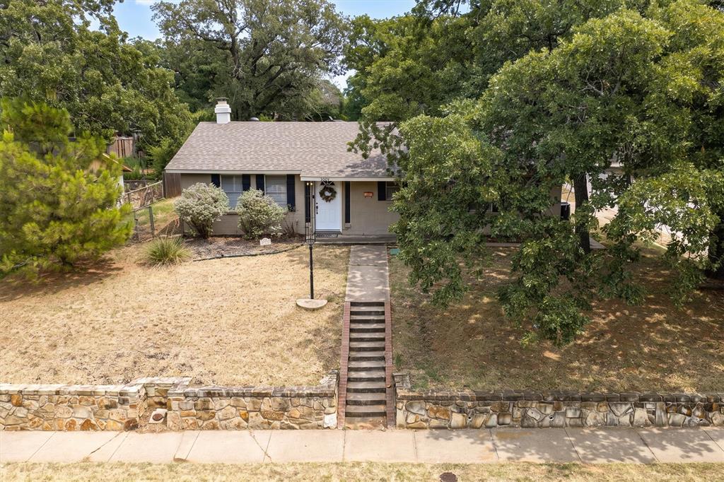 Adorable 3 bedroom, 2 bath home in a fantastic location in Grapevine!  Just minutes from restaurants, shopping, historic downtown Main St. and DFW airport!  This cozy home sits up on a hill and has a long, covered front porch perfect to enjoying morning coffee or a conversation with a friend.  As you walk into the home, you enter into the large, open living and formal dining areas.  Kitchen features eat in dining area with doors leading to small courtyard.  Open shelving on either side of the large kitchen window where the sink faces, large pantry and gas range. One bathroom is connected to two bedrooms and has a large garden tub, separate shower and sink.  Additional bathroom in hallway has shower-tub combo.  Roof is less than a year old, replaced in October 2025.  Luxury Vinyl Plank flooring throughout main areas and bedrooms; ceramic tile in bathrooms. Side entry, 2 car garage with built in shelving and cabinets.  Washing Machine and Dryer hook up in garage.  Door from garage leads to fenced in backyard area.  This home is in a great location and is ready for its next owner!