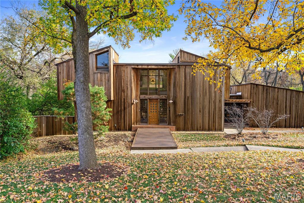 This redwood-clad contemporary, designed by architect Charles E. Fleming as his own modern sanctuary, radiates coolness! Completely renovated yet true to its original spirit, the home seamlessly connects to nature through walls of windows and outdoor spaces that make the private 1.12-acre setting feel like a modern treehouse retreat. A dramatic two-story foyer opens to a warm, tree-lined living room with a fireplace and deck access. The reimagined kitchen pairs a large island with sleek oak cabinetry, stainless steel appliances, and a butler's pantry. Another large flexible space at the front of the home would make a perfect formal dining room and living room. Upstairs, the light-filled primary suite features a skylit bath and a walk-in closet with built-in storage. Two additional bedrooms and a bathroom complete the second level. The original spiral staircase leads to a walkout lower level featuring a recreation room with a bar, a bedroom, a bath, and a laundry room with a dog wash. Walkout access leads to the covered patio with a fireplace that steps out to the pool, hot tub, and putting green. A bridge leads you over the pool to the guest house apartment, which includes a sauna, kitchenette, circular dome window, and a two-car garage. Another bridge in the yard takes you to an almost secret flat lot. An additional two-car garage is attached to the main house.