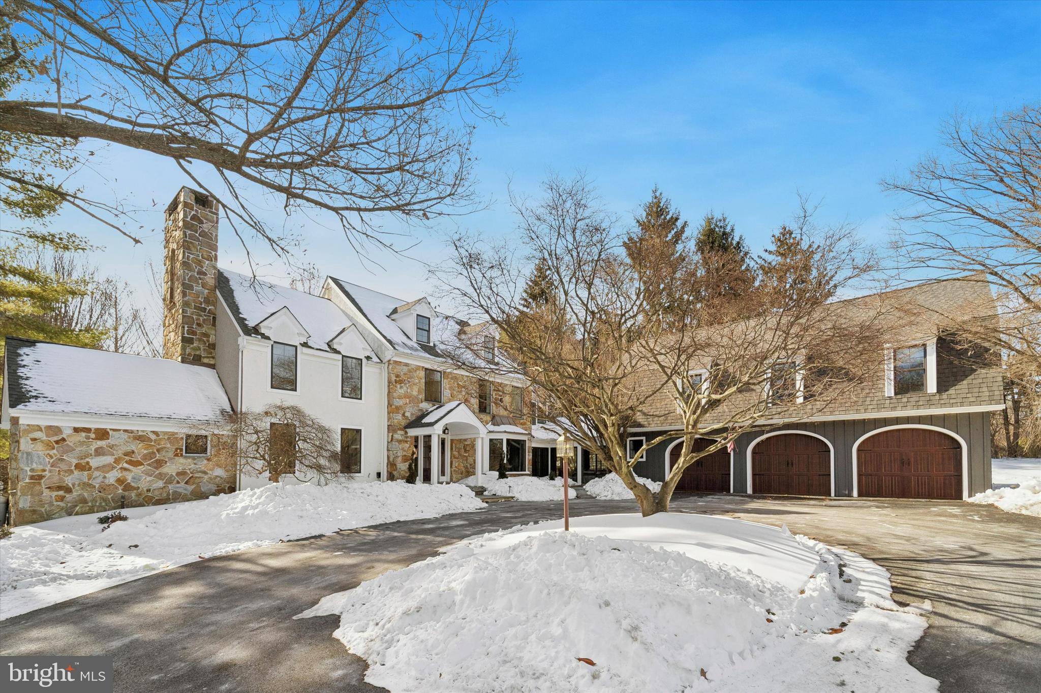 Beautifully custom and truly one of a kind, this exceptional residence sits on nearly 2-acres of serene land and is designed for those who value character, space, and thoughtful separation of living areas—far from cookie-cutter in both layout and lifestyle. Shadow Oak is widely regarded as one of Malvern’s most beloved neighborhoods for its peaceful, tree-lined streets with friendly ambience and classic charm. The connecting streets and cul-de-sacs are perfect for walks, biking, and neighborly interaction. Set back along a long driveway with a circular approach, 1148 Shadow Oak welcomes you with a bluestone walkway leading to a covered entrance and a dramatic 2-story center hall foyer with a graceful curved staircase.The main level offers an effortless blend of elegance and comfort. A bright living room features a marble-surround gas fireplace and sliding doors to the deck, flowing  into a cozy den/office with vaulted ceilings, floor to ceiling stone gas fireplace and French doors for privacy. Across the foyer, the formal dining room showcases a bay window and glass-front doors opening to the kitchen—perfect for seamless entertaining. The kitchen is truly the heart of the home, thoughtfully updated and beautifully appointed with quartz countertops, stone backsplash, select glass-front cabinetry with 2 beverage centers, a 6-burner cooktop, new Thermador double ovens, 42” Sub-Zero refrigerator, built-in drawer microwave, center island with seating for 4, a walk-in pantry, and a dining area suitable for 8-10 people.. A mudroom and 4 coat closets add everyday convenience, while the adjacent family room impresses with a massive floor to ceiling stone wood-burning fireplace, Palladian window, and sliders/door leading to both outdoor living spaces. Outdoor entertaining is exceptional, featuring a brick and stone patio with sitting wall and outdoor fireplace, a completely fenced inground gunite (new)pool with waterfall, and expansive travertine patio. The pool house includes a granite bar, lounge area and storage, creating a truly private resort-style setting. Also on the main level is a sun-filled solarium (currently used as office) with heated slate floors, which connects to the oversized 3-car detached garage. Above the garage, a private apartment offers ideal flexibility for an in-law suite, au pair, or teen retreat, complete with a kitchen area, large great room with built in bookshelves, bedroom, and full bath. The 2nd floor of the main house features a stunning primary suite with gas marble fireplace, sliding doors to a private balcony, and a serene sitting area perfect for morning coffee. The walk through custom closet is expansive, featuring a granite island and dual furniture-style sinks, leading to a spa-like bath with soaking tub, granite vanity, and water closet. Three additional bedrooms and a hall bath complete this level. The 3rd floor offers a large, finished bedroom with walk in closet—ideal for a music studio, art studio, or additional private retreat. The lower level is nothing short of spectacular, designed for entertaining and relaxation with a family room, granite bar, temperature-controlled wine cellar, guest bedroom, full bath, home gym area, and hardwood flooring.Recent owner improvements enhance both form and function and include a new roof and gutters, all new windows and skylights, 11 new exterior doors and sliders, 3 new garage doors, a newly paved driveway, wide-plank wood flooring in the kitchen, updated kitchen cabinetry and quartz countertops, new Thermador double ovens, granite countertops in multiple bathrooms and the apartment kitchen, heated slate flooring in the solarium, new carpet on the second floor, 2 new HVAC systems, a new 80-gallon water heater, fresh exterior paint, updated Azek trim, and updated hardware and lighting.This is a home that offers flexibility, privacy, and endless possibilities—perfect for multigenerational living, creative pursuits, and unforgettable gatherings.