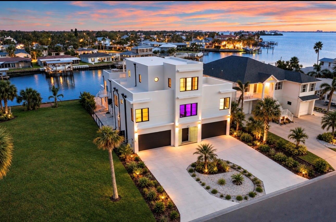 Step into a world where architectural brilliance meets coastal resilience. This extraordinary 2022 Art Deco-inspired waterfront estate combines modern design, exceptional engineering, and uncompromising construction against the breathtaking backdrop of Florida’s Gulf. This three-story residence features five bedrooms and five bathrooms, designed to maximize spectacular water views. Extensive solid reinforced concrete construction, including five wall-mounted reinforced concrete floors, gives the home a true fortress-like quality and level of structural engineering rarely found in residential construction.Reinforced concrete floors and walls, hurricane-rated PGT black vinyl windows and doors, superior flood protection, a commercial-grade TPO roof, two Trane A/C units, and spray foam insulation were thoughtfully incorporated for strength, longevity, and efficiency. A private elevator connects all three floors. Three bedrooms feature en-suite bathrooms, while expansive second- and third-floor balconies showcase stunning Gulf views. Approximately 1,300 sq. ft. of elevated outdoor deck space provides an incredible setting for entertaining and waterfront living.The resort-style saltwater pool and heated hot tub/spa create a private waterfront retreat. Controlled LED lighting and dusk-to-dawn exterior lighting beautifully highlight the home after sunset. Impact-glass rear vertical doors frame picturesque waterfront views and seamlessly connect indoor and outdoor living. An oversized spiral staircase connects the pool deck to the main outdoor living area.The remarkable oversized garage accommodates up to nine vehicles and features a mini-split A/C system, making it ideal for a car collection, gym, workshop, entertainment lounge, or conditioned workspace. Hurricane-impact garage doors provide additional durability and protection.The state-of-the-art kitchen features Bosch stainless steel appliances, a KitchenAid convection oven, sleek cabinetry, and high-end finishes. Modern technology includes two Smart LED WiFi fireplaces, a 400-amp electrical system prepped for a boat lift, a 220V electric-car charging station, and pre-wired outlets for additional ceiling fans, recessed lighting, or custom disco-ball lighting. Outside, an easy-to-maintain disco-ball-inspired pool finish, extensive hardscaping, and low-maintenance landscaping complete the property.Located in one of Dunedin’s most coveted waterfront neighborhoods, the home provides convenient access to the Pinellas Trail and Dunedin Causeway for kayaking, paddleboarding, and scenic bike rides. Downtown Dunedin is approximately 15 minutes away by bike, boat, or car, offering restaurants, breweries, shopping, festivals, and entertainment. Honeymoon Island and some of the area’s most treasured coastal destinations are also nearby. The empty lot to the east belongs to the neighboring property, helping preserve the open feel and unobstructed views.With unparalleled Gulf views, world-class engineering, reinforced concrete construction, hurricane-conscious design, sophisticated technology, extraordinary garage capacity, and resort-style amenities, this home offers a combination rarely available in the Dunedin luxury market. More than a luxury waterfront residence, this is a private coastal fortress—engineered and built to an extraordinary standard. Whether a private retreat, entertainer’s dream, automotive enthusiast’s haven, or boater’s paradise, this exceptional property is truly one of a kind.