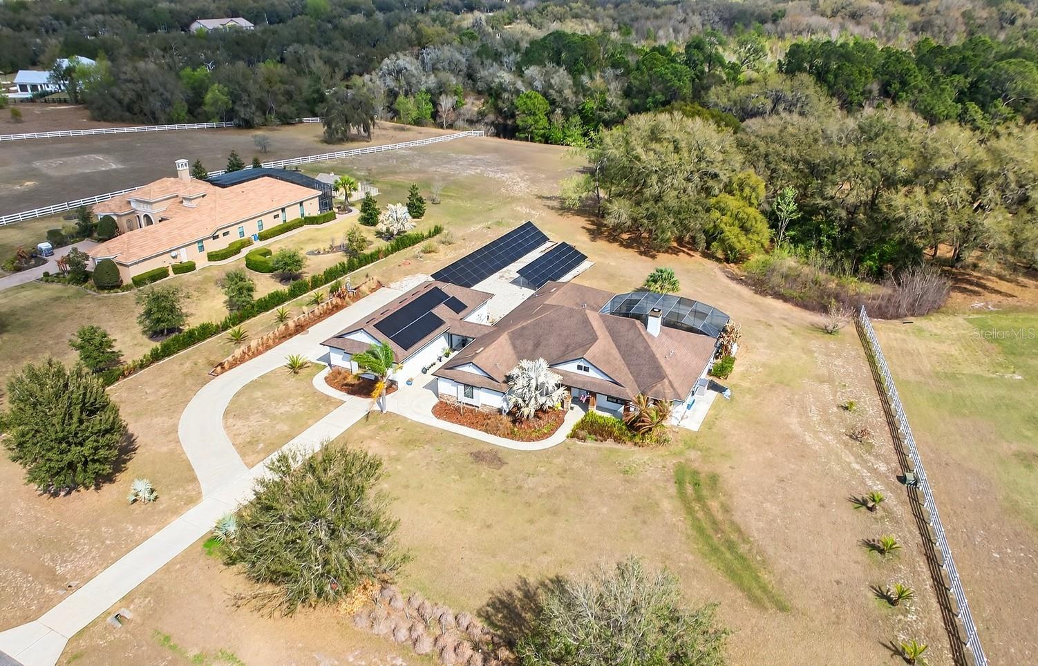 Set on 2.32 PICTURESQUE ACRES inside the GATED ~ EQUESTRIAN COMMUNITY of Beauclair Ranch Club, this CUSTOM BUILT ~ 6-bedroom / 4-bath ~ POOL HOME with a 4-car detached garage offers the perfect blend of privacy, luxury, and energy-efficient living! Major updates lead the way, including ***FULLY OWNED SOLAR PANELS that are currently providing COMPLETE ENERGY COVERAGE*** – often producing a monthly surplus, a BRAND NEW COOKTOP (2026), EXTERIOR PAINT (2023), and septic service completed in (2023). A 210 ft well and double-pane windows add to the home’s long-term efficiency and peace of mind. From the moment you arrive, the property’s expansive setting and scenic views create an impressive first impression. The home’s detached 4-car garage with workshop space is connected by a covered walkway, offering plenty of room for vehicles, hobbies, storage, or recreational equipment. The original 3-car garage has been thoughtfully converted into a spacious sixth bedroom with a full bath, making it an ideal IN-LAW SUITE, guest retreat, or private living quarters. Inside, elevated design details are found everywhere you turn, including CROWN MOLDING throughout, ENGINEERED HARDWOOD flooring in the main living areas, and a light, bright OPEN CONCEPT layout designed for both everyday living and entertaining. The 3-WAY SPLIT BEDROOM floor plan provides excellent separation of space, and nearly every bedroom features walk-in closets. The home offers a variety of functional spaces including a FORMAL DINING room, a dedicated OFFICE with a built-in desk, and a convenient MUDROOM/laundry room. At the center of it all is the gorgeous chef’s kitchen, designed to impress with an OVERSIZED ISLAND offering seating on both sides, granite countertops, rich cabinetry, decorative backsplash, STAINLESS STEEL APPLIANCES, beverage refrigerator, and the brand new cooktop with a custom range hood that seamlessly matches the cabinetry. The kitchen flows effortlessly into the light filled casual dining space and the spacious living room, making it an entertainer’s dream! The living room features a timeless stacked-stone WOOD BURNING FIREPLACE and TRIPLE SLIDING GLASS DOORS that open wide to the COVERED LANAI and SCREENED POOL & SPA, creating the ultimate INDOOR/OUTDOOR Florida lifestyle. The PRIMARY SUITE is privately positioned away from the other bedrooms, offering a peaceful retreat with a decorative tray ceiling, abundant natural light, direct access to the lanai and pool, a sitting area, DUAL WALK-IN CLOSETS, and a well-appointed en-suite bath featuring dual sinks and a massive CUSTOM WALK-IN SHOWER. Outside, the sprawling property provides beautiful open views, privacy, and room to breathe, all within the sought-after Beauclair Ranch Club, a gated equestrian community known for its spacious homesites and serene setting. Despite the peaceful acreage lifestyle, you are just off SR 448 with quick access to US-441, making it easy to reach shopping, dining, and daily conveniences throughout Mount Dora, Tavares, and the surrounding Lake County area. With fully owned solar, a flexible multi-generational layout, resort-style pool living, and acreage inside a gated equestrian community (bring your horses!), this exceptional property truly offers everything you could want in a home. Some furnishings are negotiable, making it even easier to move right in and start enjoying the lifestyle. Call today to schedule a tour! **Seller may consider buyer concessions if made in an offer **