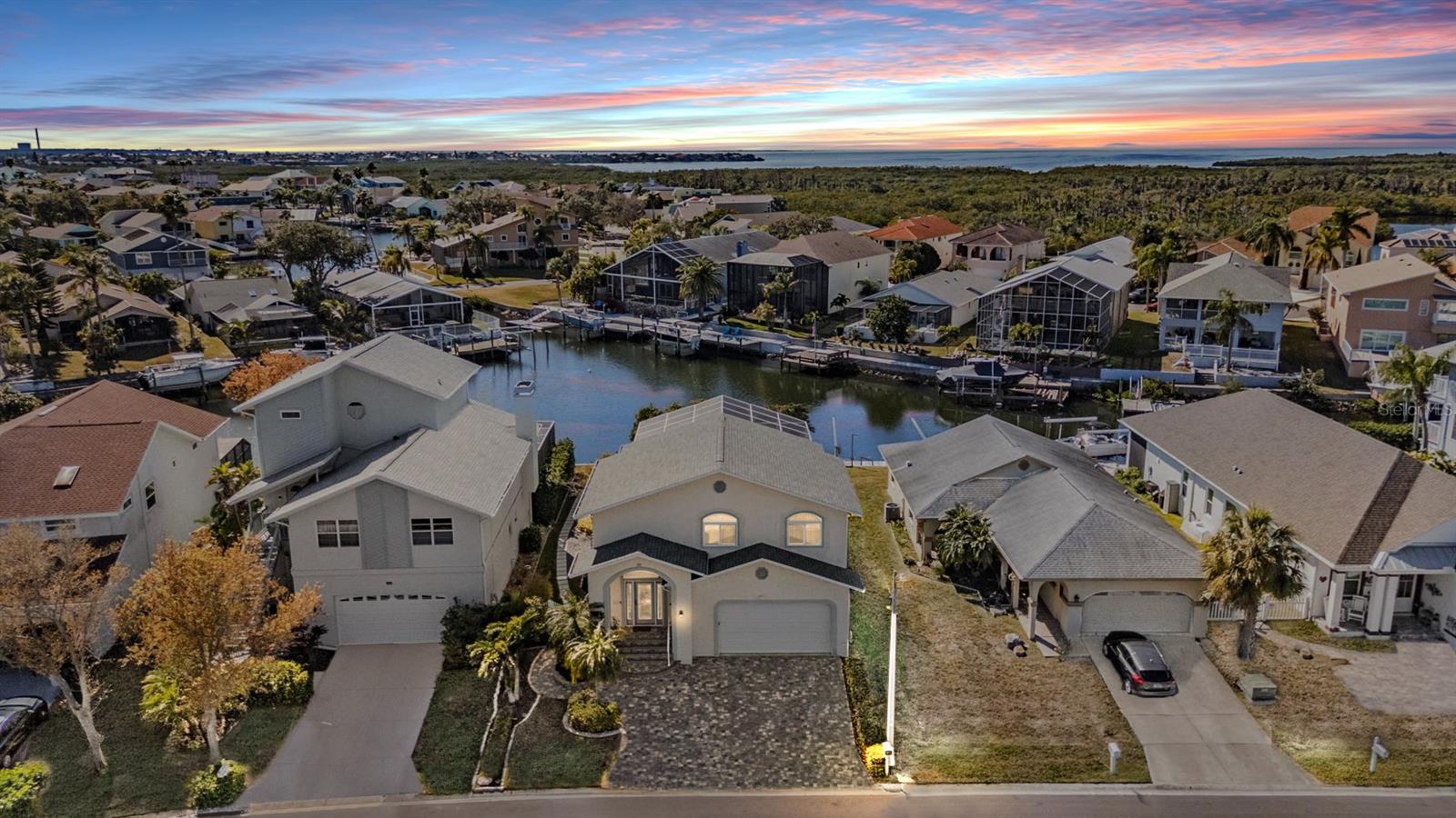 Inviting waterfront living awaits in this beautifully updated, Never Flooded, 4 Bedroom, 3.5 Bath Pool Home, located in the coastal community of Gulf Harbors Sea Forest. Set on an extra-wide canal with direct Gulf access, not restricted by any bridges -  this move-in-ready residence offers a comfortable floor plan with tranquil water views and seamless indoor-outdoor living. The paver driveway leads to a welcoming entry and a spacious great-room layout featuring luxury vinyl flooring throughout the main level. The remodeled kitchen is thoughtfully designed with marble countertops, stainless steel appliances, custom cabinetry with ample storage, a farmhouse sink, decorative backsplash, and breakfast bar—ideal for everyday living and entertaining. The open layout provides unobstructed views of the backyard, pool, and canal beyond. The main-level primary suite is generous in size and includes dual walk-in closets, an updated spa-like bath with dual vanities, ceramic tile, a soaking tub, and step-in shower. An additional bedroom on the first floor offers flexibility for guests or home office use, along with a convenient half bath nearby. Upstairs, a loft area provides space for an office or play area, with access to a full bath shared by an oversized bedroom. A separate upstairs bedroom suite features abundant natural light, a large closet, and a private bath with walk-in shower. Step outside through brand new Hurricane Impact Sliding Doors to a covered lanai overlooking a heated pool, koi pond, and fenced backyard—perfect for relaxing or entertaining while enjoying peaceful water views. The property also features a  floating dock, irrigation system, impact glass or hurricane protection for all windows and doors, a two-car garage with extra storage, a 2021 roof replacement, 2021 water heater, and 2018 a/c system. Residents enjoy access to community amenities including tennis and pickleball courts, playgrounds, walking trails, clubhouse, a community private boat ramp, and a private Gulf-front beach club which is one of only two private beaches in Florida. Just minutes from downtown New Port Richey, shopping, dining, parks, and waterfront restaurants, this home offers a well-balanced blend of comfort, convenience, and the Florida waterfront lifestyle.