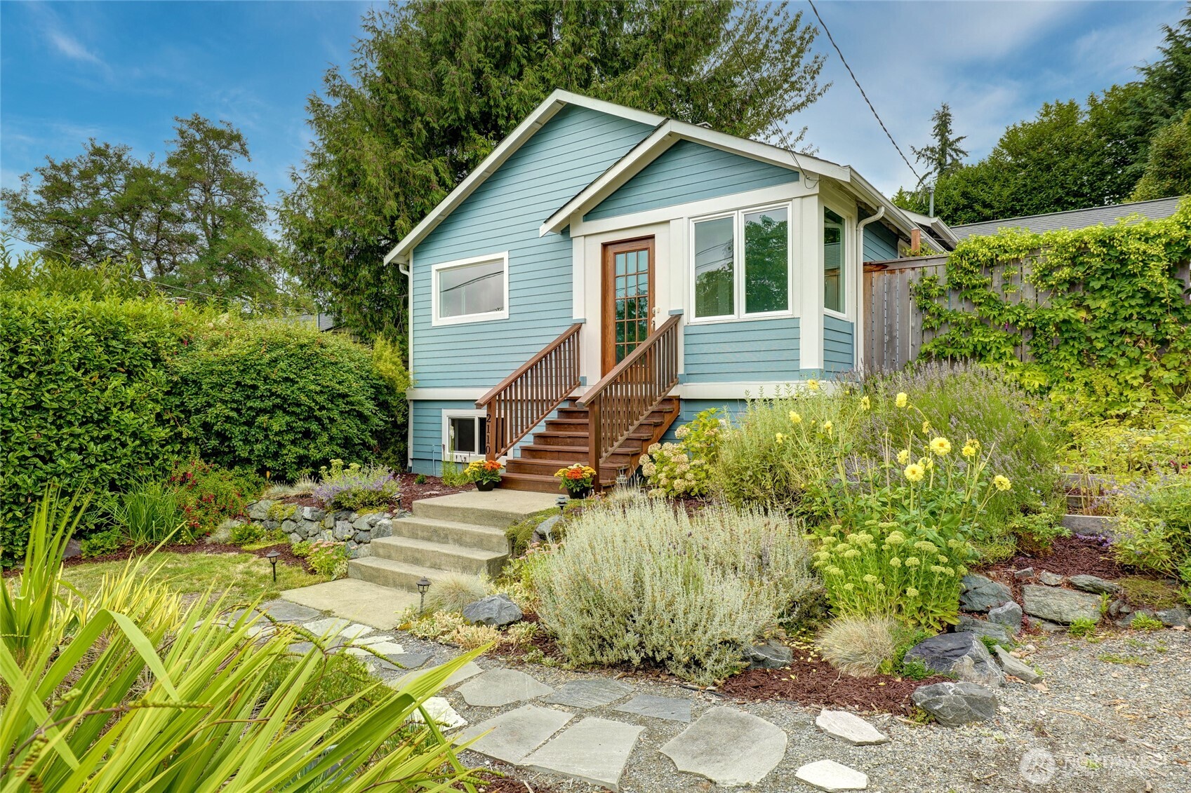 Enjoy a quiet and serene setting near Green Lake with easy access to everything this prime location offers. Welcoming entry boasts a charming sunroom and opens to the spacious interior that is flooded in natural light.  Thoughtful updates, beautiful hardwood floors and flexible living spaces are present. Generous living room offers cozy fireplace.   At the heart of the home is an enormous modern kitchen with eating area and direct access to the backyard, making indoor-outdoor living and entertaining effortless. Cozy family room/den is a great feature.  Main level offers two bedrooms and stylish bath.  Downstairs includes a bonus room, bedroom, bath, storage and is full of potential for primary suite, MIL, guest suite or home office. Step outside to discover multiple outdoor living spaces, garden shed and beautifully established gardens, creating your own private oasis.  EV Charger + plenty of parking. Fantastic Location! Easy access to Light Rail, Green Lake, Northgate & Downtown. Everyday living that is both convenient & flexible.