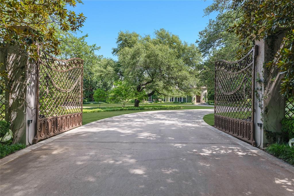 Commanding 2.3 acres at the distinguished corner of Park Lane and Ravine in Preston Hollow, this rare first offering captures the homeowner’s vision crafted by Richard Drummond Davis Architects. Shaped by the landscape architecture of Naud Burnett, a sweeping drive emerges beneath a canopy of mature live oaks, leading to a composed flagstone approach. Spanning 11,331 square feet, the residence reveals a refined interplay of limestone, rich walnut, and storied European elements. An iron front door, drawn from the grandeur of a private Roman estate, opens to interiors defined by French-sourced mantles and 19th-century doors, each detail a considered acquisition. A paneled library with wet bar opens to the gardens, while the formal dining room, wrapped in imported paneling and mirrored accents, reflects a sense of enduring elegance. Living and family rooms extend seamlessly to the covered veranda, dissolving the boundary between interior and landscape. The kitchen offers warm wood cabinetry, and a substantial stone island, supported by a fully appointed butler’s pantry. A climate-controlled wine room holds more than 5,000 bottles, while the outdoor kitchen continues the experience with a wood-burning oven and open-fire cooking. The primary suite unfolds as a private retreat with sitting area, dedicated dressing room, bespoke built-ins, coffee bar, and balcony overlooking the grounds. Dual baths and expansive custom closets complete the space. Three additional ensuite bedrooms, along with a fitness room, craft room, and staff office, complete the upper level. The stunning veranda opens to the expansive lawn designed for entertaining at any scale. A quatrefoil-shaped pool, cabana with kitchenette and bath, winding stone pathways, and composed garden rooms complete this private estate—one of Preston Hollow’s most distinguished offerings.