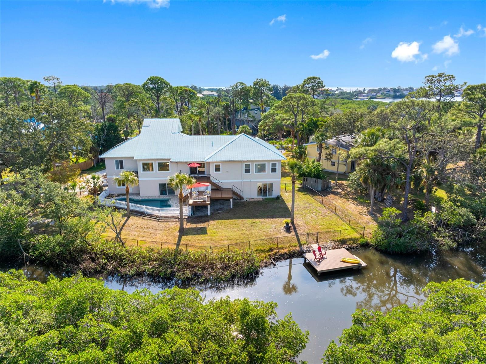 Custom-built in 2005, this elevated eco-friendly coastal retreat sits in the highly coveted north end of Tarpon Springs, FL. Equipped with SOLAR PANELS, this spacious 3,503 sq. ft., 4-bedroom, 4-bath + bonus loft is situated on .55-acres and is perfectly located just minutes from the Gulf and Fred Howard Park. Enjoy peaceful conservation and water views right from your backyard, complete with a MULTI-LEVEL TREX DECK, a SALTWATER Pebble Tec POOL, and a NEW TREX DOCK with Direct Gulf Access, island beaches, and waterfront restaurants—ideal for boating, fishing, kayaking, and paddleboarding. With NO HOA Restrictions, this home is an excellent fit for large families, multigenerational living, or short-term and vacation rentals. Arrive on the elevated main level and step into a bright, open living space enhanced by soaring ceilings and hurricane-impact windows that fill the home with natural light. The chef-inspired kitchen features a walk-in pantry, new quartz countertops, and a 10-foot bar-top island perfect for casual dining and entertaining. The expansive Primary Suite includes a luxurious bath with a walk-in shower, soaking tub, dual sinks, and a large walk-in closet. Bedroom two serves as an ideal guest suite with its own en-suite bath, while bedrooms three and four are spacious and share a full bathroom. The versatile bonus loft is ideal as a home office, craft room, playroom, or creative studio—flexibility to suit your lifestyle. An additional 2,341 sq. ft. lower level (not included in the sq footage) provides endless flexibility with space for storage, a game room, workshop, or entertainment area, along with an oversized 2-car garage. Elevated on a concrete foundation with pilings, this home is engineered to thrive in coastal conditions. Located near top-rated Tarpon Springs schools, stunning Gulf beaches, parks, boat launch, Downtown Tarpon Springs, and the world-famous Sponge Docks, this property offers the perfect blend of comfort, privacy, and convenience in one exceptional home.