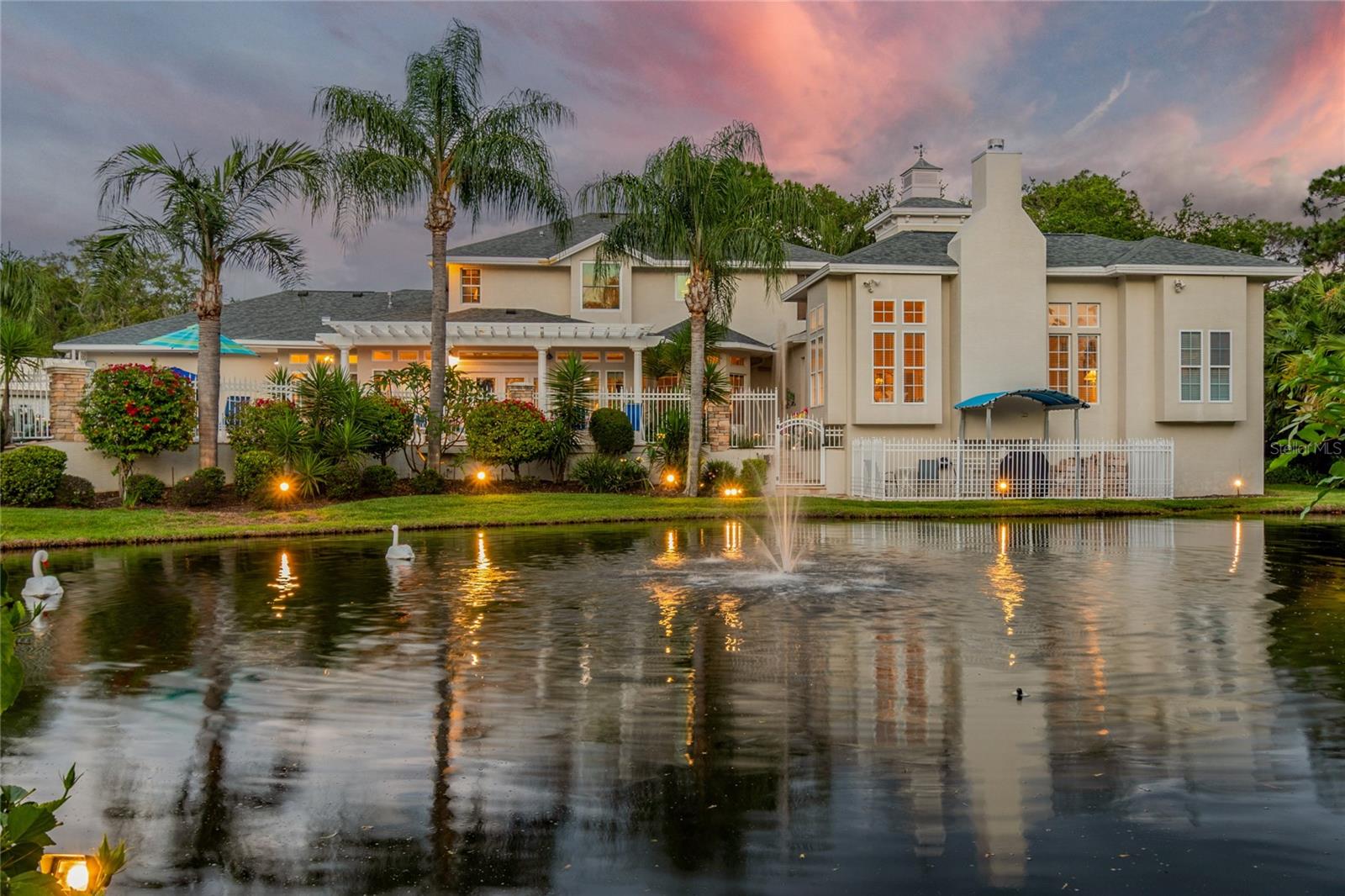 Nestled within the exclusive gated enclave of Riviera, this stunning waterfront estate sits on nearly one acre at the end of a private cul-de-sac with over 140 feet of direct waterfrontage, your own private pond, and Gulf access via the Anclote River. From the moment you arrive, soaring coffered ceilings, rich hardwood floors in every bedroom, elegant tile throughout the main living areas, and exquisite double crown molding set the tone for the level of quality and craftsmanship found at every turn. The recently upgraded chef's kitchen is appointed with quartz countertops, professional-grade Miele appliances, and a Thermador glass cooktop — ideal for entertaining at any scale. A second full kitchen in the sunroom extends your entertaining possibilities even further, offering panoramic views of the lush, meticulously manicured landscaping that surrounds this magnificent estate. Three fireplaces — a gas fireplace in the living room and two classic wood-burning fireplaces — add warmth and architectural elegance to the living spaces, while the open layout flows effortlessly throughout, perfectly suited for large family gatherings. A thoughtfully designed in-law suite on the main level is currently owner-occupied as the primary bedroom, while a full second-floor primary suite offers additional flexibility — ideal for multi-generational families or those who simply desire options. Additional highlights include a whole-house water filtration system and generator hookup for added comfort and peace of mind. Outside, stepping into the backyard is an experience unto itself — a truly tranquil retreat where the sounds of nature, shimmering water views, and lush surroundings instantly melt the day away. A heated saltwater pool serves as the centerpiece of a resort-style backyard framed by breathtaking waterfront scenery. The 10,000 lb covered boat lift and floating dock provide direct Gulf access via the Anclote River — putting the Tarpon Springs Sponge Docks, Caladesi Island, and the open Gulf within easy reach. A new tubular seawall reinforces and protects this exceptional waterfront property for years to come. Dolphins, manatees, and native wildlife are frequent visitors to this remarkable setting. Located just minutes from Trinity shopping, dining, and medical facilities. Zoned for top-rated Trinity-area schools. This is a rare opportunity to own one of the finest waterfront estates in all of Tampa Bay.