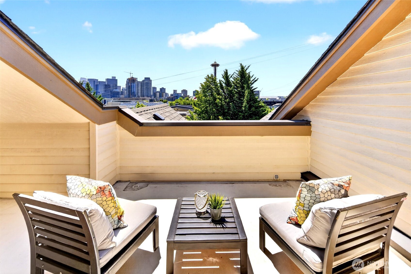 The best homes on Queen Anne sit on quiet blocks and put the whole neighborhood within reach; this is one of them. This three-level townhouse is well-appointed throughout, with hardwood floors on the main level leading into an updated kitchen with new stainless appliances, a gas range, and generous counter space framed by bar seating that keeps the chef in the conversation. The south facing living room is sun-filled and spacious. Every bedroom has its own en suite bath, and the primary is a true retreat, with bay windows, a distinctive curved accent window, and Space Needle views greeting you every morning. Fresh carpet on the lower and upper levels, soaring vaulted ceilings, and skylights give each floor its own character. Above it all, a private rooftop deck with sweeping Space Needle, Climate Pledge Arena, and city views and room for a full outdoor dining setup. The fenced backyard is tidy and low-maintenance, with space for a grill and seating. A one-car garage and additional driveway parking offer something Seattle buyers know not to take for granted. Situated at the bottom of Queen Anne Hill, downtown and South Lake Union are an easy commute from your door. Seattle Center and Climate Pledge Arena are in close proximity, with Kerry Park, Ward Springs Park, and Queen Anne Ave shopping and dining just up the hill. Everything is in place. Come experience it in person.