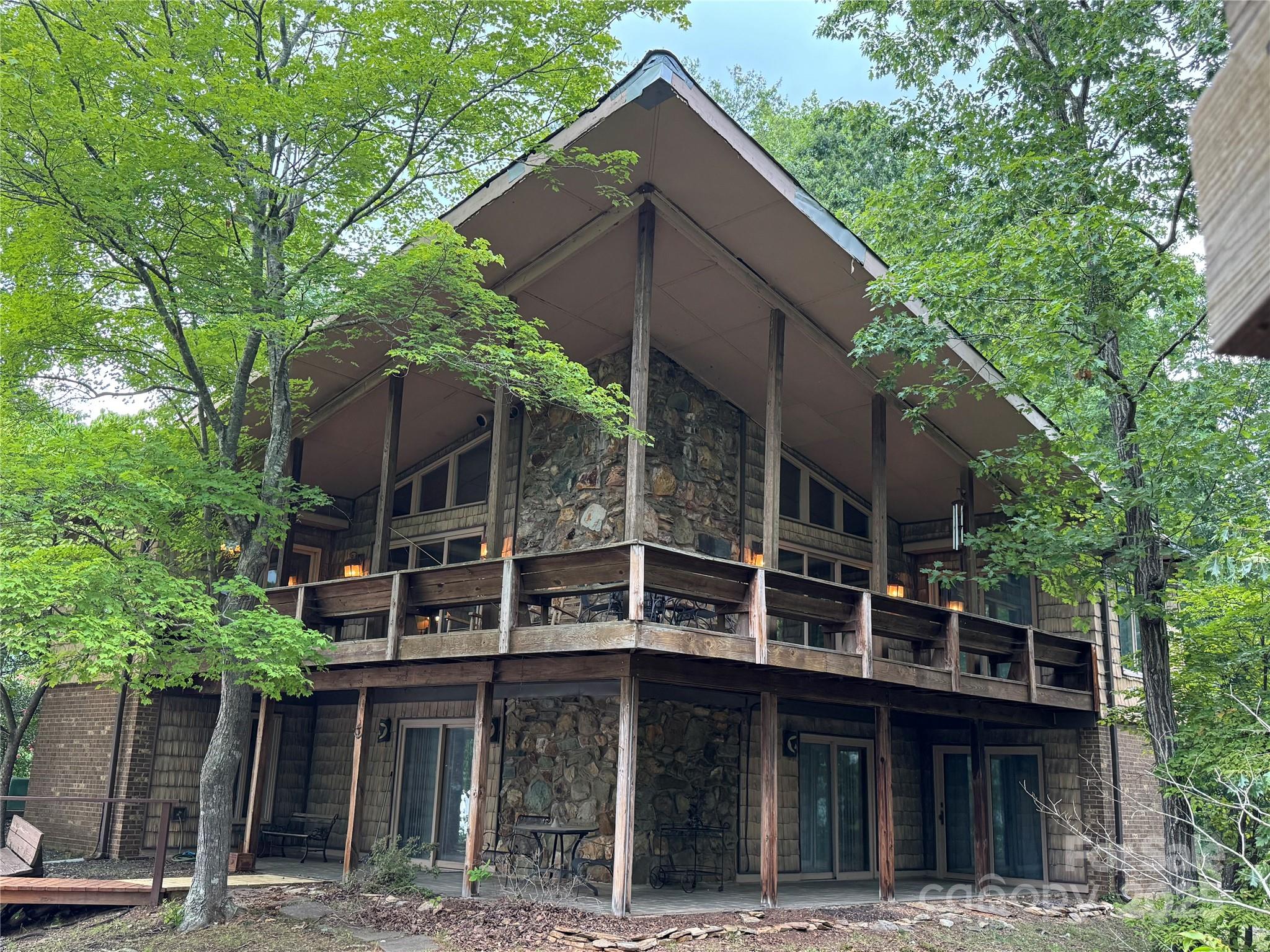 The VIEW of a lifetime is an understatement for this PENINSULA lot as it juts out into the water. The Boat dock is on one side of this POINT in a cove, and a large Dock on the opposite side on the main channel sits across from Uwharrie National Forest. Water surrounds you, as you observe from the beautifully placed Gazebo just at the Lot's Point. There is room for many visitors as there are 3 bedrooms 1.5 baths on the main level, and three flex rooms with a common area in the basement. WATER VIEWS FROM ALMOST EVERY ROOM. As you walk in the main area of the home, take in the beautiful large stone fireplace with floor to ceiling windows on each side with beautiful LAKE views. Wood floors and wood ceilings in this main area bring your eye upward to see the large expansive A-frame ceiling. Owner wants another family to enjoy this space fully, so they are including a Tri-toon, Paddle boat, and (John Boat with no motor) with the sale of this home.  Home needs some repairs, SOLD AS IS.