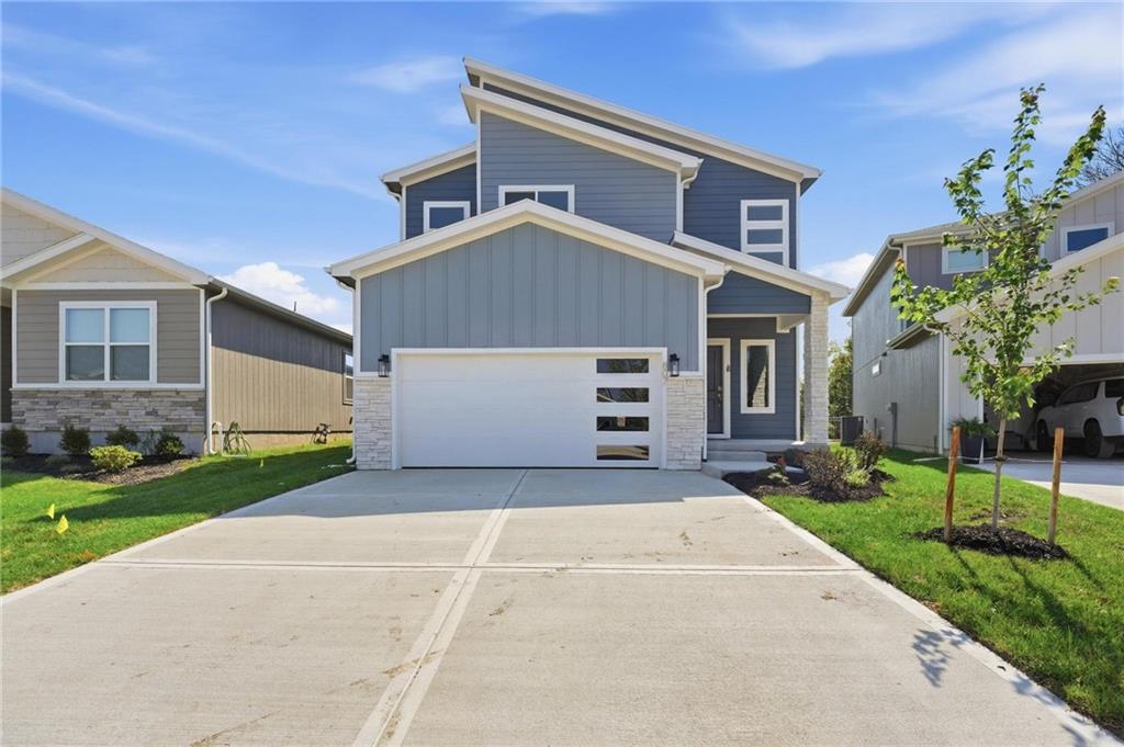 Move IN READY The NEW Jasmin 1.5 story by Avital Homes. Featured in the Fall Parade of Homes this bold architecture, clean lines, and thoughtful design create a gorgeous and efficient home.  The eye-catching exterior with welcoming covered porch reveals a sweeping 2 story foyer with dramatically wainscoted walls. Beyond, the open main level is designed for both quiet comfort and social entertaining. The natural light-filled living room with striking fireplace wall flows seamlessly into the dining area and kitchen where a large island, walk-in pantry, soft-close cabinetry and designer selected finishes provide both form and function.  Tucked privately on the main, a dual entry primary suite offers a relaxing retreat with a beautifully trimmed accent wall, ensuite bath and generous closet space. Just off the garage entry, a convenient mudroom with built-in bench and adjacent laundry room (connected to primary) keeps things organized and efficient. Upstairs, you'll get three big additional bedrooms with walk-in closets, a large double-vanity hall bath and a versatile loft space ideal for study space, play area, or built-ins.   Relaxing evenings on the large covered patio that looks out to green space and trees tops it all off.  The home is equipped with energy-efficient lighting, high efficiency HVAC and water heater, Low-E windows, soft-close cabinetry throughout, a fully insulated garage and the confidence of 1/2/10 year warranties.  This particular home is built on a slab-on-grade foundation with hidden staircase and 2nd level storage space, maximizing living space while keeping your entry price lower.  Located in sought-after Creekmoor, residents enjoy a championship golf course, the best clubhouse and amenities complex in KC with 3 pools, a fitness center, sports courts, walking trails, stocked lake, convenient access to shopping, dining, and more!