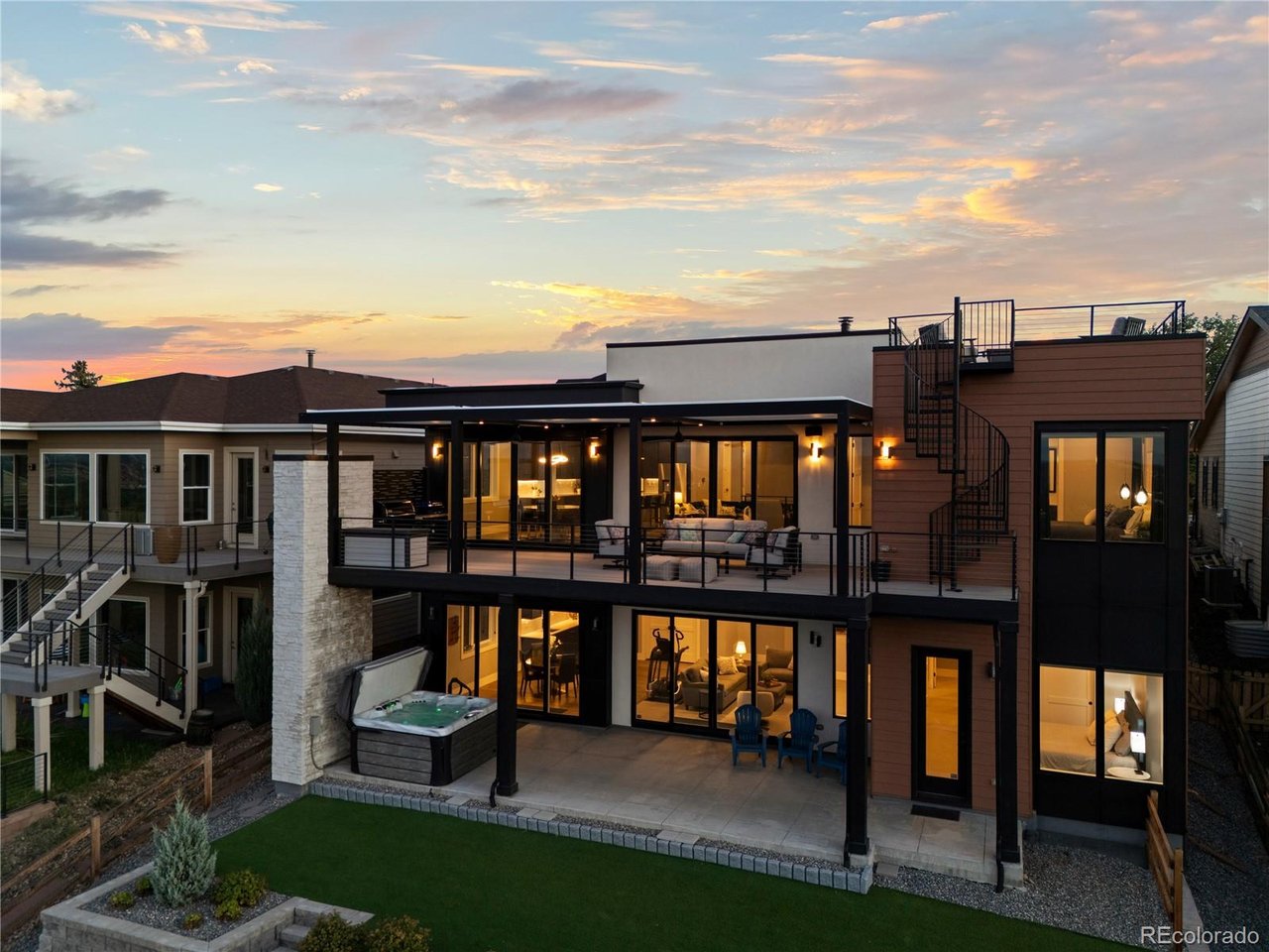 Sitting on top of the world, this one-of-a-kind home captures breathtaking panoramic views of downtown Denver, Pikes Peak, and the entire Front Range. From sweeping mountain vistas and dramatic sunsets to the glow of the city lights after dark, the setting is truly extraordinary-and the home was designed to take full advantage of it. Custom-built in 2023 by Sheffield Homes, this modern ranch is filled with natural light, with two sets of multi-panel glass doors framing the views and creating a seamless connection to the outdoors. A dramatic great room with a gas fireplace flows into the sleek, minimalist kitchen, where custom cabinetry, JennAir appliances and a generous island create a polished backdrop for cooking and gathering. Five bedrooms include a serene primary suite with a beautifully finished contemporary bath, while the finished lower level offers generous space for movie nights, game days, guests, or relaxed evenings at home. A wall of glass opens to the expansive outdoor living spaces, seamlessly extending the home toward the incredible views. Outside, the views become even more spectacular. The expansive main deck features an electric pergola with independently controlled sections for sun or shade, integrated drainage & outdoor fans, creating an incredible place to enjoy the Colorado landscape throughout the day. Unwind in the hot tub as the sun sets over the mountains, then follow the spiral staircase to the home's true showpiece-a rooftop deck with remarkable 360-degree views stretching from the Denver skyline to Pikes Peak & across the Front Range. A natural gas firepit sets the stage for sunset cocktails, Fourth of July fireworks & unforgettable nights under the Colorado sky. Solar panels, an EV charger, a whole-house steam humidifier, and easy-care landscaping add thoughtful convenience. Modern, beautifully designed & positioned to capture a perspective that is nearly impossible to replicate, this is a truly special home. www.ArvadaModernLiving.com