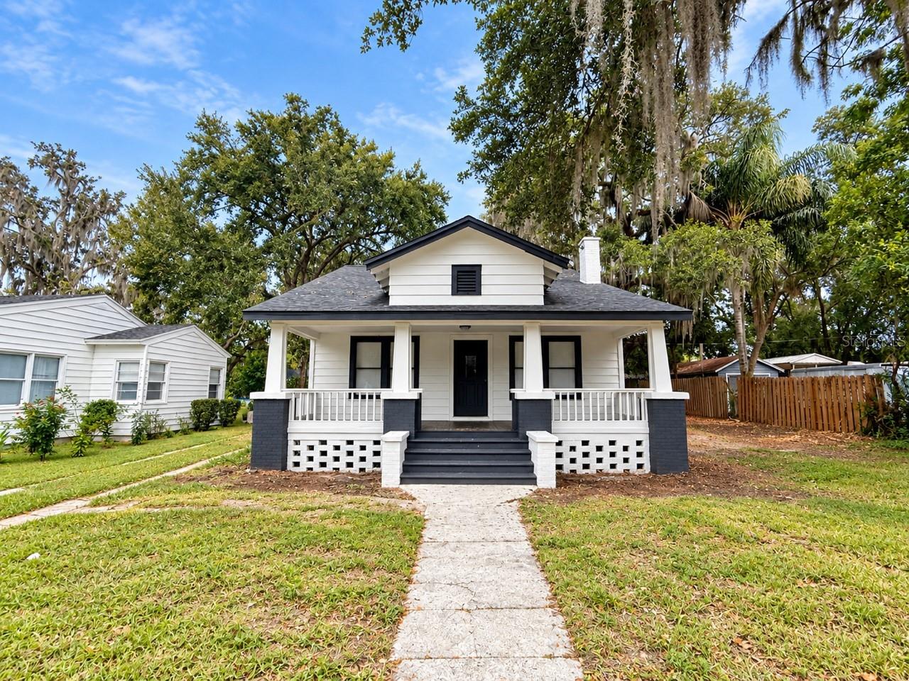 Welcome to this beautifully remodeled Colonial-style home where timeless character meets modern design, just minutes from Downtown Leesburg! From the moment you arrive, the classic black-and-white exterior, mature trees, spacious lot, and expansive covered front porch create an unforgettable first impression.Inside, nearly every detail has been thoughtfully updated with new flooring, modern lighting, crown molding, fresh finishes, and custom touches throughout. The beautifully remodeled kitchen features white shaker-style cabinetry, quartz-style countertops, gold hardware, an oversized black sink with statement faucet, and brand-new stainless-steel appliances. The spacious living room retains the home’s original charm with a beautiful brick fireplace and abundant natural light. The versatile four-bedroom, two-bath floor plan features the primary bedroom and an additional bedroom downstairs, with two additional bedrooms and a full bathroom upstairs. Both bathrooms have been beautifully remodeled with marble-look tile showers, contemporary vanities, matte-black fixtures, and modern finishes. Enjoy the oversized covered front porch, spacious yard, and mature Central Florida setting, all just minutes from the shops, dining, entertainment, and historic charm of Downtown Leesburg. Convenient to Central Florida’s lakes and recreation, the greater Orlando area and its world-famous attractions, with Florida’s beaches within reach for an easy day trip. Beautifully remodeled, full of character, and truly move-in ready—schedule your private showing today!