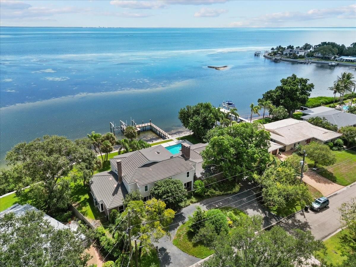 Stunning Panoramic 147 feet of WATERFRONT views, a large private boat dock with TWO boat lifts, and a private POOL located on the peak of the bay kissing the water that didn't have any water intrusion or damages during the record-breaking hurricanes in 2024? You're not dreaming. It’s REAL. This spacious plantation-style home is the perfect blend of Old Florida character and modern luxury. Tucked away on a large private lot on the peak of the curved bay, this magnificent property is surrounded by a variety of views, fruit trees, exotic plants, and tropical wildlife. With almost every room having a beautiful view of the sparkling water, you’ll never forget why you chose this as the place to call home. You'll immediately be greeted by water views through the grand entryway into the dining room as you move past the beautiful cantilever staircase wrapping up to the second floor. The endless water views from the open kitchen and living area are breathtaking. Talk about a perfect place to entertain! The spacious open living/kitchen area features an enormous kitchen with island, built-in Sub-Zero refrigerator, Elise range and gorgeous unique countertops, large bar with separate sink, unique, rare, and authentic Florida Keystone coral rock fireplace, and impact sliding glass doors out to the back lanai, making indoor/outdoor entertaining a breeze. Words cannot describe the views from outside. Whether you want to swim in the private pool, have dinner on the lanai, watch the wildlife with your coffee, or hop on the boat from your dock with not one, but TWO boat lifts…this home has you covered…and a view of the water from almost every angle. There is space for all of your toys on this expansive dock and room for all your outdoor activities in the large yard along the water. This home features a library with floor to ceiling solid wood shelving and a fireplace that is like something out of a fairy tale! If the library isn't cozy enough, there's a total of THREE fireplaces throughout the home. With 5 bedrooms and 5 and a half bathrooms, you’ll have enough space for everyone. There’s even a bonus room with a view that would make working from home, exercising, or whatever you want to do in there seem like you're still on vacation somewhere! The covered balcony of the second floor runs the length of the home, giving the bedrooms along the back not only a view from their window, but a place to step outside and FEEL the bay breeze. This home was designed to enjoy the views as both stories have an outdoor space that runs the entire length. The FIRST FLOOR BEDROOM has an exterior door leading out to the back lanai and is large enough to be an in-law suite, a second primary bedroom, or transformed into a game room. The sky is the limit for this unique space.Impact windows throughout, slate tile roof, new pool heater/chiller, luxury appliances, wet bar with wine fridge, ice maker, and liquor cabinet with lock, 15 minutes to The Don Cesar and Gulf Beaches, 12 minutes to all the action of downtown St. Petersburg, 30 minutes from Tampa, and 45 minutes from Sarasota…you will NOT find a better location. Be close to everything, but far enough to be in your own world. Properties like this are RARE. Waterfront properties that encountered ZERO damages during last year's hurricanes are RARE. Private docks with TWO boat lifts are RARE. If you were waiting for the perfect pool home on the open water with a dock with not one, but TWO boat lifts, THIS. IS. IT.