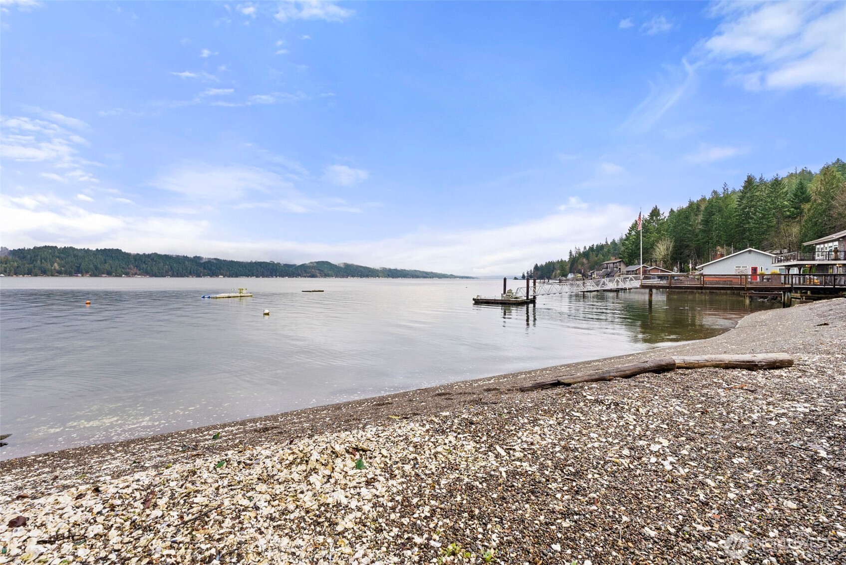 Discover the pinnacle of the Pacific Northwest, an exquisite waterfront escape where the rugged Olympic Mountains meet the tranquil, shimmering waters of the Hood Canal. This residence is more than a home; it is a curated front-row experience to nature’s nightly masterpiece. Directly situated on the shoreline, the property offers private beach access to one of the world’s most coveted marine environments. Spend your afternoons kayaking and paddleboarding, or indulge in the quintessential canal lifestyle by harvesting world-famous oysters and clams directly from your own backyard. The open kitchen and expansive living area flow seamlessly onto a sprawling entertainment deck, creating an idyllic setting for sunrise coffee or sunset soirées.The MAIN floor also includes a well-appointed BEDROOM and full bath, offering effortless single-level living. Upper Level: Features an additional bedroom, full bath, and a versatile bunk room. The upper level opens to a massive view deck, providing a premier vantage point and also possibly more square footage. Added value comes from MOORING BOUY, NEWER PRIVATE septic, and NEWER PRIVATE well.  Home also has a PROVEN vacation RENTAL history; AirBnb and Furnished Finders. Easy access to hospitals for traveling nurses. Positioned just moments from the iconic Twanoh State Park, you are granted immediate access to miles of verdant hiking trails and the warmest saltwater beaches in the state. Your coastal escape awaits.