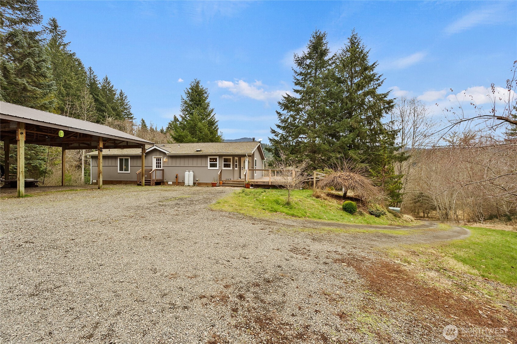 Private PNW retreat on 5 secluded acres with Burley Mountain views! Motivated seller - don’t miss this opportunity. This updated 2-bed, 2-bath home features a beautifully remodeled kitchen with granite countertops, high-end appliances, and stone accents behind the dual-fuel range, new matching LVP flooring throughout, and a spacious partial wraparound deck for enjoying the peaceful setting.    3-bedroom septic allows potential for a third bedroom, guest suite, or ADU. This homestead-ready property includes a secure chicken coop, mature orchard, garden space, and a new greenhouse. Level RV parking with 30-amp power hookup adds flexibility for guests or extra living space.    Outbuildings include a 30x42 detached shop/garage with 14x30 carport plus an additional, detached 26x36 carport near the utility room entrance. Seasonal creek, established landscaping, and great southern exposure for year-round light. Close to Gifford Pinchot access and surrounded by wildlife—privacy, functionality, and outdoor living all in one!