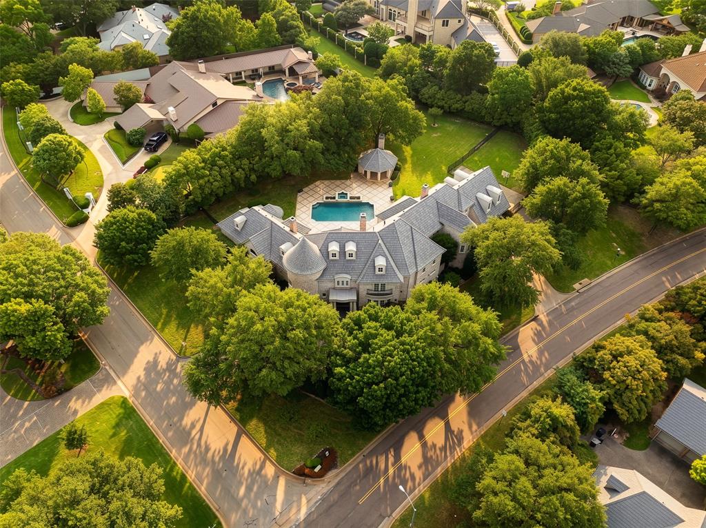 Situated on an expansive .88-acre corner lot in the sought-after Preston Trails neighborhood, this impressive 6,800-square-foot estate blends luxury, comfort, and functionality. Designed for both daily living and entertaining, the home features a bright, open family room lined with walls of windows that flows seamlessly into the breakfast area and gourmet kitchen, complete with Thermador appliances, Custom cabinetry, a large center island, designer lighting, and abundant storage. The main-level primary retreat offers a private sitting area perfect for an office or exercise room, vaulted ceilings, custom built-ins, and a cozy fireplace creating a peaceful escape with tons of space. Its spa-inspired bath includes a soaking tub, separate walk-in shower, and dual walk-in closets. A private guest suite with its own bath is also conveniently located downstairs. Ideal for hosting, the formal living and dining spaces are introduced by a grand foyer with spiral staircase and complemented by a stylish wet bar. Upstairs, the home continues to impress with a theater-style game room featuring a wet bar and kitchenette perfect for MIL quarters, an additional living area, and three spacious ensuite bedrooms. Outdoors, the resort-inspired backyard is designed for year-round enjoyment with multiple entertaining spaces, a sparkling pool, a gazebo with fireplace, lush green lawn space, mature trees, and beautifully illuminated landscaping. Located only a stone's throw to Bent Tree Country Club and Preston Trails Golf Club, top-tier private schools, DFW and Love Airports, and the best Dallas has to offer. Private Neighborhood Security for added peace of mind!