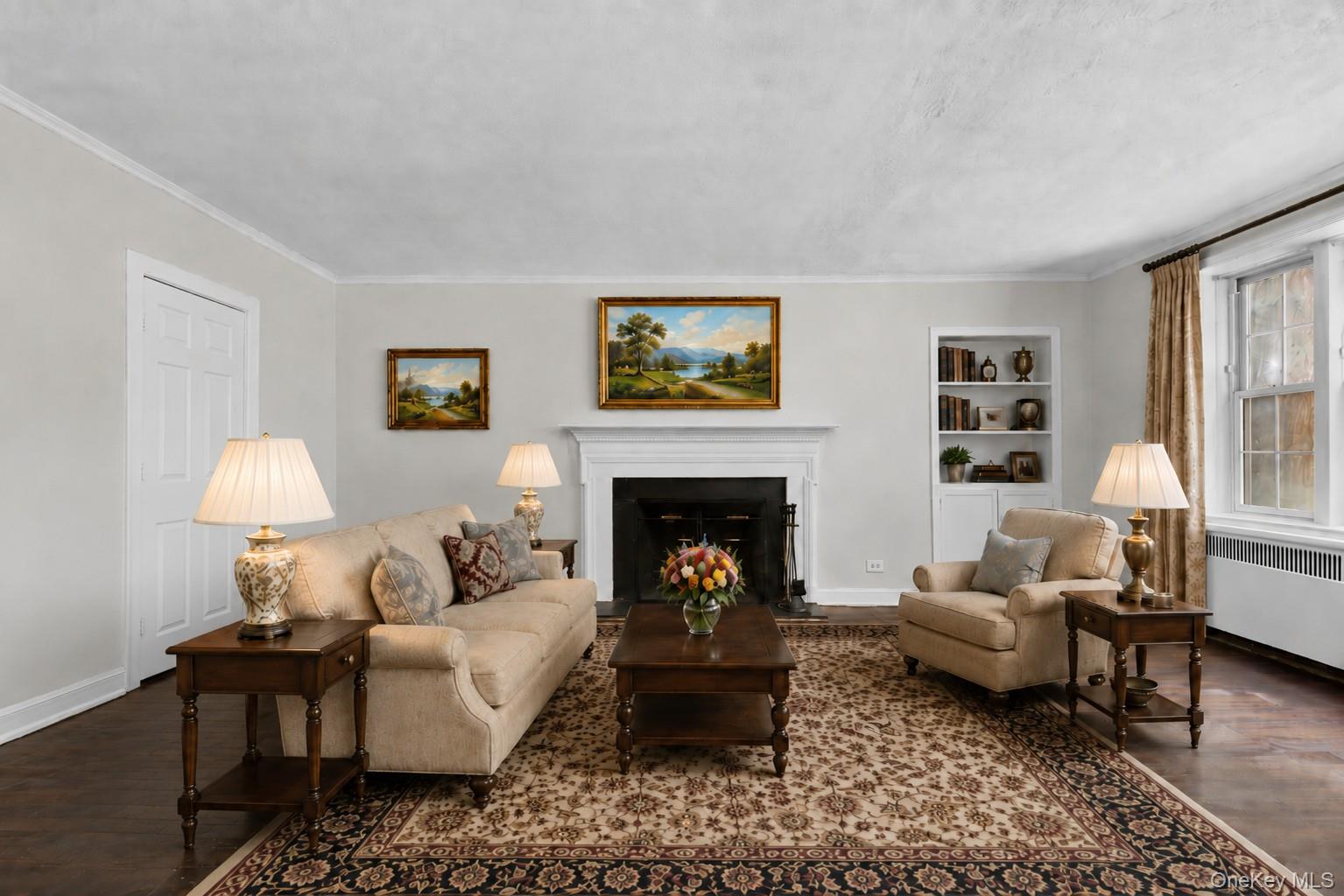 Welcome to a peaceful retreat nestled among the trees in the foothills of Hartsdale. Pinewood Gardens is a beautifully landscaped complex that offers a wonderful sense of seclusion while keeping you close to everything—just one block from Central Park Avenue and approximately 0.7 miles from Hartsdale Village and the Metro-North train station.This desirable first-floor corner unit offers easy, no-step access and an abundance of natural light from windows on multiple exposures. The spacious living room features a working wood-burning fireplace, built-in cabinetry and shelving, and hardwood floors that continue into the dining area.The primary bedroom offers a walk-in closet and windows with elevated views from two exposures, while the second bedroom provides flexibility for use as a bedroom, home office, den, or guest space.Step outside and enjoy the community's inviting outdoor amenities, including a playground, BBQ area, and gathering space, all surrounded by mature trees and green space. Laundry facilities and additional storage are conveniently located in the building's basement.Parking is plentiful, free, and unassigned for residents and guests, with garage parking available by waitlist.