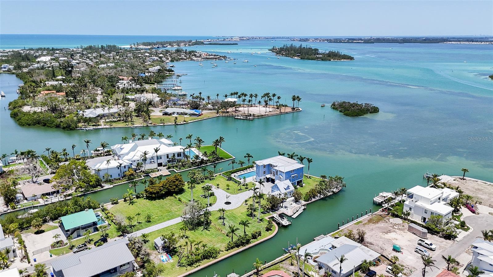 This stunning Bayfront estate delivers over 680 feet of pristine Bayfront waterfront on nearly an acre and a half of prime point property. True Longboat Key gold. Special features of this home include five bedrooms, five full bathrooms, hardwood floors, sky-high ceilings plus walls of glass. The home opens to multiple covered terraces built for soaking in endless Bay views and the best of Florida living at its finest. The open-concept layout blends indoor comfort with outdoor style, perfect for hosting or unwinding in total privacy. The kitchen is sleek and spacious with high end Wolf package and Sub Zero ready for gourmet meals or casual bites with a view.  The adjoining family room also features a large stone fireplace. The primary suite is a retreat all its own with private terrace access, spa-style bath and water views that never quit. Outside, the lifestyle really takes off. A large Bayfront resort-style pool with a hot tub anchors the backyard, surrounded by multiple fire pits perfect for evening gatherings under the stars. Need space for guests? A separate guest house is available to design to your personal touch, offers total privacy and comfort, ideal for hosting family or friends without sacrificing your own space. This estate isn’t just a home it’s a waterfront playground built for bold living. There are two existing docks with a 15,000 pound lift. There's kayak storage and room for multiple docks and all your water toys. The new seawall built in 2010 adds peace of mind. There is a four car garage. This North Longboat property is a must see for anyone seeking a luxurious lifestyle combined with natural beauty. With its modern amenities, prime location, and stunning views, it stands out as a dream home. Don’t miss the opportunity to make this exquisite residence your own. This north Longboat location is near many outstanding restaurants and Anna Maria Island. Watch dolphins and manatees and so many Florida birds glide past your backyard. The azure waters of the Gulf of Mexico and the beach are just steps away.