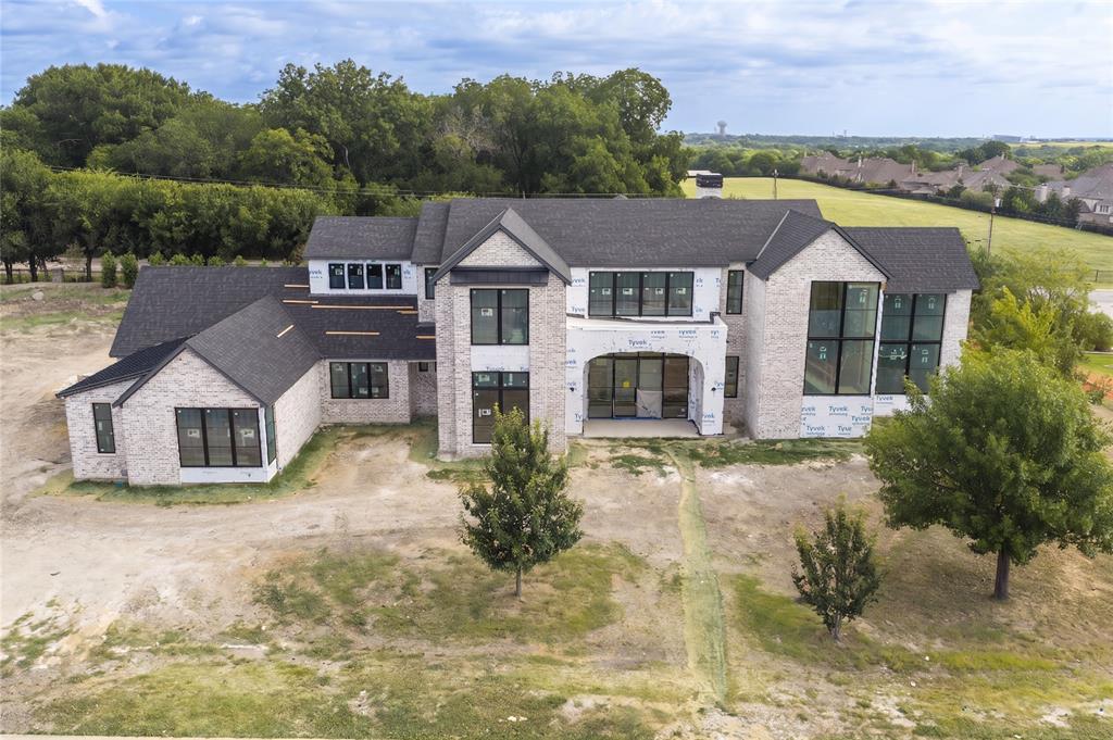 Brand-new construction by Tim Jackson Custom Homes, one of North Texas's most respected luxury builders for three decades, on a private 1.2-acre lot in Twin Oaks, an exclusive nine-home enclave in Fairview built around a community pond, water features, and a walking trail, all within top-ranked Lovejoy ISD. The 8,091-square-foot modern traditional design combines painted brick and cast stone with standing-seam metal roof accents, a two-story entry, and tall steel-framed windows. Inside, a brick-paver foyer and floating staircase open to a great room with a gas fireplace, which connects to a kitchen finished with Sub-Zero, Wolf, and Cove appliances, custom cabinetry, and a quartzite island, where the farm sink looks out over the pool. A full prep kitchen and walk-in pantry handle the work behind the scenes. Off the main living areas, a wine room sits near the entry, and a brick-walled study offers built-ins and a spiral stair up to a private loft. The first-floor primary suite includes a sitting area set off by a see-through fireplace and a marble bath with a freestanding tub, oversized shower, dual vanities, and two walk-in closets. A guest suite sits on the main level, and upstairs, three more ensuite bedrooms, a second living room, a game room, and a carpeted media room with a wet bar. Two powder baths and separate upstairs and downstairs laundry rooms complete the plan. Out back, there's a pool with a raised spillover spa, a two-story covered loggia with motorized retractable screens, an outdoor kitchen, and a firepit, all framed by mature trees with full irrigation, fencing, and dark-sky lighting. Built with full spray-foam encapsulation, Energy Star efficiency, a Lennox Signature Series HVAC system, structured wiring, and an oversized four-car garage with epoxy floors, this is a brand-new custom estate on a private acre-plus in one of Fairview's most premier communities.