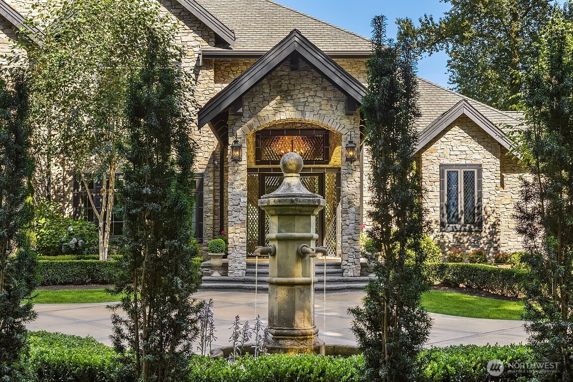This gated, private Estate blends refined craftsmanship with modern elegance. Granite façade, leaded glass entry, and Renaissance water feature create grand first impression. Inside, soaring ceilings, curved floating staircase, herringbone hardwoods, and striking millwork define luxurious living. Primary spa bath w/Grecian marble shower, clawfoot tub, and heated travertine floors. Chef’s kitchen w/Calacatta marble island, mother-of-pearl backsplash, and Bertazzoni gas range extends to breathtaking grounds. Seamless indoor/outdoor flow to entertainment terrace, firepit, heated pool, pool house bath, and stone cabana. Moments from Woodinville’s top schools and wine country, this Estate offers elevated living in a truly exceptional setting.