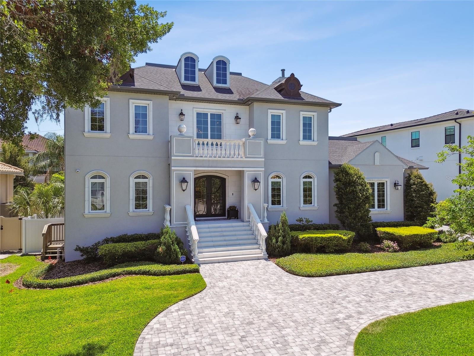Chateau Bryant introduces a rare blend of timeless design and modern amenities, set within the distinguished Sunset Park community. A grand double staircase foyer with a 23-foot ceiling, marble flooring and crystal chandelier introduces the home’s elegant scale. The chef’s kitchen features Wolf and Sub-Zero appliances, dual islands, a walk-in pantry, and a separate butler’s pantry—designed for entertaining and everyday function. A custom climate-controlled wine cellar, designed with exotic wood racking, offers a sophisticated space for collection storage and display. Five spacious en suite bedrooms, rich hardwood flooring throughout, and a dedicated home office provide comfort and versatility. The upstairs bonus room and fully equipped laundry suite add modern convenience. The owners’ retreat includes a sitting area, custom island closet, and a marble-appointed bath with soaking tub and walk-in shower. Outdoors, enjoy a heated saltwater pool with sun shelf, a full summer kitchen with granite counters, and lush fishtail palms for privacy. Zoned for Mabry, Coleman and Plant schools, this estate offers timeless design in a premier Tampa location.