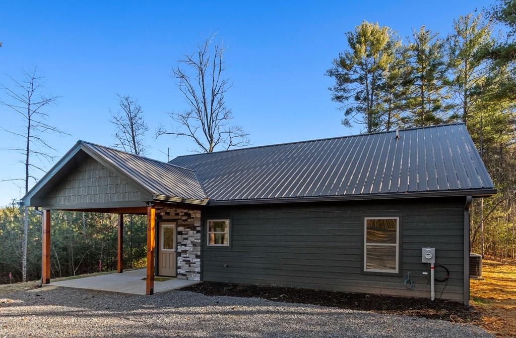 A new home by one of Murphy's best home builders! This charming single-level 2-bedroom, 2-bathroom NEW CONSTRUCTION cabin is on almost one wooded acre, just minutes from town. Designed for comfort and style, this home with LP smart siding offers easy access with no steps to the full-length covered porch with tongue and groove ceiling and a stone entry. Inside, the spacious Great Room features wide plank oak floors that extend throughout the home, a vaulted tongue-and-groove ceiling, and a cozy gas log fireplace, creating a warm, inviting gathering space. French glass doors open to the porch, blending indoor and outdoor living. The kitchen includes granite countertops, a center island, and knotty pine cabinets. Both bedrooms are designed for comfort, with two full baths showcasing quality tile finishes. The exterior boasts a durable charcoal metal roof and LP wood siding for long-lasting appeal and low maintenance. Hurry to make this new home yours!
