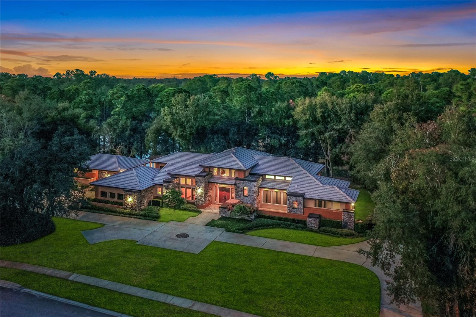 4 ACRES in gated Summer Oaks in Lake Mary’s sought-after Markham Woods Corridor WITH GUEST HOUSE!! This Frank Lloyd Wright–inspired home, complete with a pool and private guest house, is truly one of a kind and presents a rare opportunity to own it all: a gated four-acre estate, breathtaking water and nature views, and an impeccably maintained residence. Behind the home lies an approximately one-acre pond, bordered by nearly two acres of protected wooded land that serves as a private wildlife sanctuary and invites exploration. Inside, the expansive floor plan features ceiling heights ranging from 10 to 18 feet, highlighted by warm wood accents, stained concrete floors with slate and wood inlays, and refined architectural details throughout. The primary suite offers a spacious walk-in closet with ample room for both his and her wardrobes. The spa-like primary bathroom features dual vanities with generous counter space, a large walk-in shower with dual shower heads, and an oversized jetted tub ideal for long, relaxing soaks. Designed for entertaining, the outdoor living spaces include four distinct areas with access from the living room, kitchen, primary suite, secondary bedroom, and guest house. The contemporary outdoor kitchen features floating cabinetry, pedestal design, stainless steel farmhouse sink with disposal, Summit refrigerator, Twin Eagles 24" power burner, a 36" grill, and a Kamado grill, all positioned to take in panoramic views of the pond and surrounding woods. The heated saltwater lap pool, equipped with an in-floor cleaning system and enclosed by a panoramic screen, sits adjacent to the main living area, kitchen, and primary bedroom. A concrete cantilevered walkway extends over the rear of the pool and showcases a six-foot water feature, while the foundation wall enhances both privacy and security for the color-changing LED-lit pool. Stone accents surrounding the pool subtly conceal a French drain system, completing this thoughtfully designed outdoor retreat. This property may be under audio/visual surveillance.