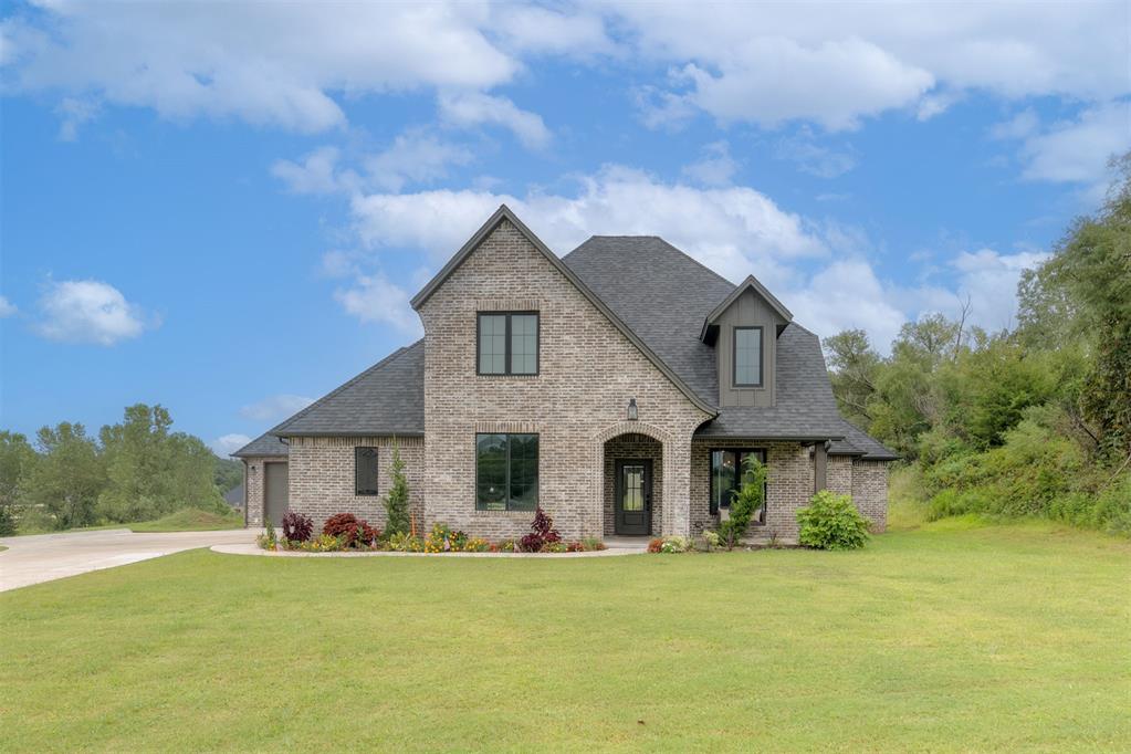 Nestled on a full acre in the gated community of Foxmor Estates, this 2022 modern farmhouse blends timeless design with thoughtful comforts, creating a home that is both warm and refined. From the moment you step inside, soaring ceilings and natural wood accents fill the open layout with light and elegance, while wide-plank oak floors add warmth and continuity. The heart of the home is the beautifully appointed kitchen, anchored by full-height shaker cabinetry, quartz countertops, and an oversized island with seating, all illuminated by bold black pendant lights. A built-in oven, gas range, and abundant storage make the space as functional as it is stunning. A barn-door study offers flexible use as a fifth bedroom or retreat, while the luxurious primary suite provides a sanctuary of its own. Its spa-inspired bath features a freestanding soaking tub beneath a globe chandelier,  dual sinks, and custom cabinetry that echoes the home’s warm wood finishes. An additional main floor bedroom with ensuite bath is perfect for guests or multi-generational living, plus an oversized mud/laundry room ensure daily life flows with ease. Upstairs, two bedrooms share an attached bath designed with both privacy and connection in mind. Outdoors, a covered patio with fireplace and freestanding hot tub invites al fresco evenings, while the expansive acre lot offers space for gardens, play, entertaining, or even a future pool, all within the serenity of a gated setting. A divided three-car garage offers ample storage and a lovely front porch with swing encourages peaceful downtime. Located in the highly rated Midwest City–Del City school district, with award-winning Schwartz Elementary just minutes away and Carl Albert schools nearby, this home delivers both convenience and top-tier education. Blending practicality, luxury, and lifestyle, 13400 SE 94th Street is more than a residence—it is a place where every detail is tailored and every moment feels special.