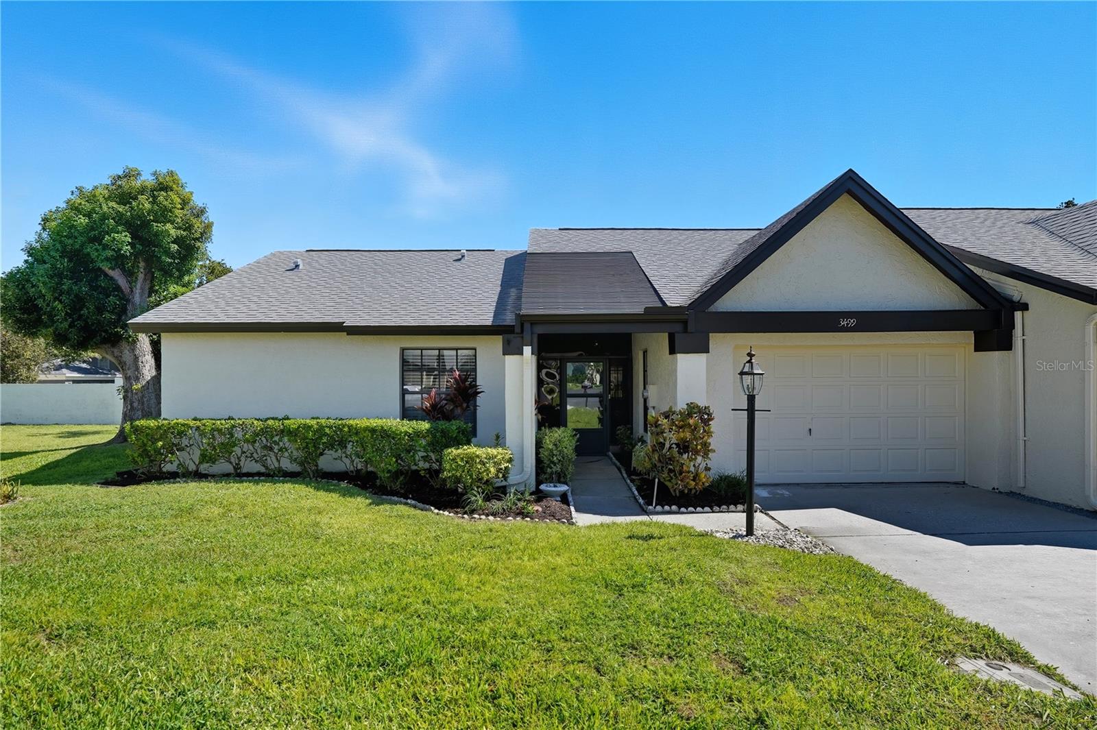 One or more photo(s) has been virtually staged. Welcome to this beautifully updated 2-bedroom, 2-bathroom villa located in the highly desirable 55+ community of Highland Lakes in Palm Harbor! This charming residence combines modern upgrades with low-maintenance living, offering both comfort and style. Highlights include a newer roof (2017), water heater (2020), and appliances (2021). The oversized attached one-car garage offers ample storage space. Step through the inviting foyer, with a convenient coat closet, into a spacious open-concept living and dining area featuring wood-look laminate flooring and plantation shutters throughout. The updated kitchen is light and bright, showcasing shaker cabinets, granite countertops, subway tile backsplash with under-cabinet lighting, matching appliances, and an updated light fixture. A separate pantry adds extra storage and convenience. The primary suite includes a large walk-in closet and a private ensuite bath with a walk-in shower. The remodeled guest bath features a new vanity, sink, and toilet, and the guest bedroom also offers its own generous walk-in closet. A bright sunroom at the back of the home provides the perfect spot to relax and enjoy the Florida sunshine year-round. Enjoy resort-style living in this ACTIVE 55+ community, which offers 3 executive golf courses, boat/RV storage, heated pools, tennis and pickleball courts, and a vibrant social calendar. Conveniently located near top dining, shopping, and beautiful Gulf beaches, this home is move-in ready and waiting for you! Don’t miss your opportunity to experience the best of Palm Harbor living. Schedule your showing today!