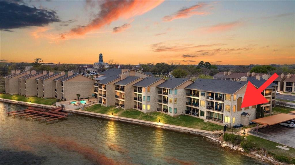 Experience the perfect blend of lakefront luxury, low-maintenance living, and walkable small-town charm in this beautifully updated 2-bedroom, 2-bath corner condominium at The Lodge on Lake Granbury. Offering approximately 1,280 square feet, this exceptional waterfront residence features panoramic lake views through expansive windows, allowing you to enjoy stunning sunsets and even Granbury’s spectacular fireworks displays from the comfort of your living room.Designed for both comfort and convenience, this condo features granite countertops, an induction cooktop, and all new appliances in 2022. Recent updates include all new windows, remote-controlled insulated shades on the lakeside, plantation shutters in the front, along with bamboo flooring in the office.Step outside to your extra-large private patio and enjoy all the benefits of lakefront living without the maintenance. Residents enjoy amenities including a private dock, swimming pool, fitness center, clubhouse, covered parking, and the convenience of additional parking and storage units available for rent on-site. HOA dues include cable, internet, water, sewer, and trash.Located just 0.1 mile from the historic Granbury Square, you’ll enjoy walking to award-winning restaurants, wineries, boutique shopping, entertainment, and year-round festivals. Adjacent to Granbury City Beach, Hewlett Park, and scenic walking trails, this home offers the best of Granbury’s vibrant, patriotic community. With no short-term rentals allowed, residents enjoy a more private and community-focused environment. Conveniently located approximately 45 minutes from Fort Worth and 75 minutes from Dallas.