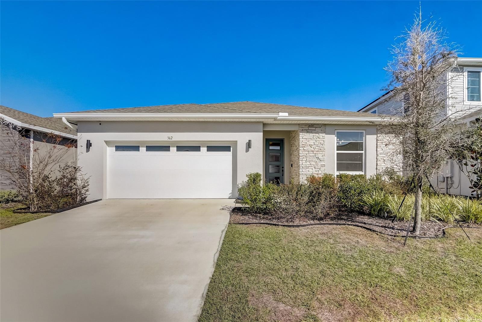 Step into this nearly-new 2022 residence in the Eden Hills neighborhood, where this terrific floor plan offers a fresh take on modern living. From the moment you arrive, the stone-accented exterior creates a warm welcome that continues inside with soaring ceilings and impressive eight and nine-foot doors. The heart of this home is a kitchen designed for real life, featuring custom cabinets with soft-close tech, quartz countertops, and top-tier General Electric appliances. Whether you’re hosting a weekend get-together in the great room—complete with a perfectly placed 72-inch TV outlet—or enjoying a quiet evening, the layout feels intentional and easy. For those working from home, the front room is already wired with Ethernet and ready for your desk. You’ll appreciate the practical upgrades too, like the matte black hardware, epoxy garage floors, and a 220-volt EV charging station. The primary suite serves as a true getaway with its deep soaker tub and frameless glass shower, while a separate ensuite bedroom offers a comfortable, private space for visitors. Located just 8 minutes from the I-4 and Publix, and within a quick 20-to-45-minute drive of Central Florida’s best shopping, dining, and theme parks, this spot hits that sweet point between neighborhood peace and city convenience. Come see how these thoughtful details come together—your new chapter starts here!
