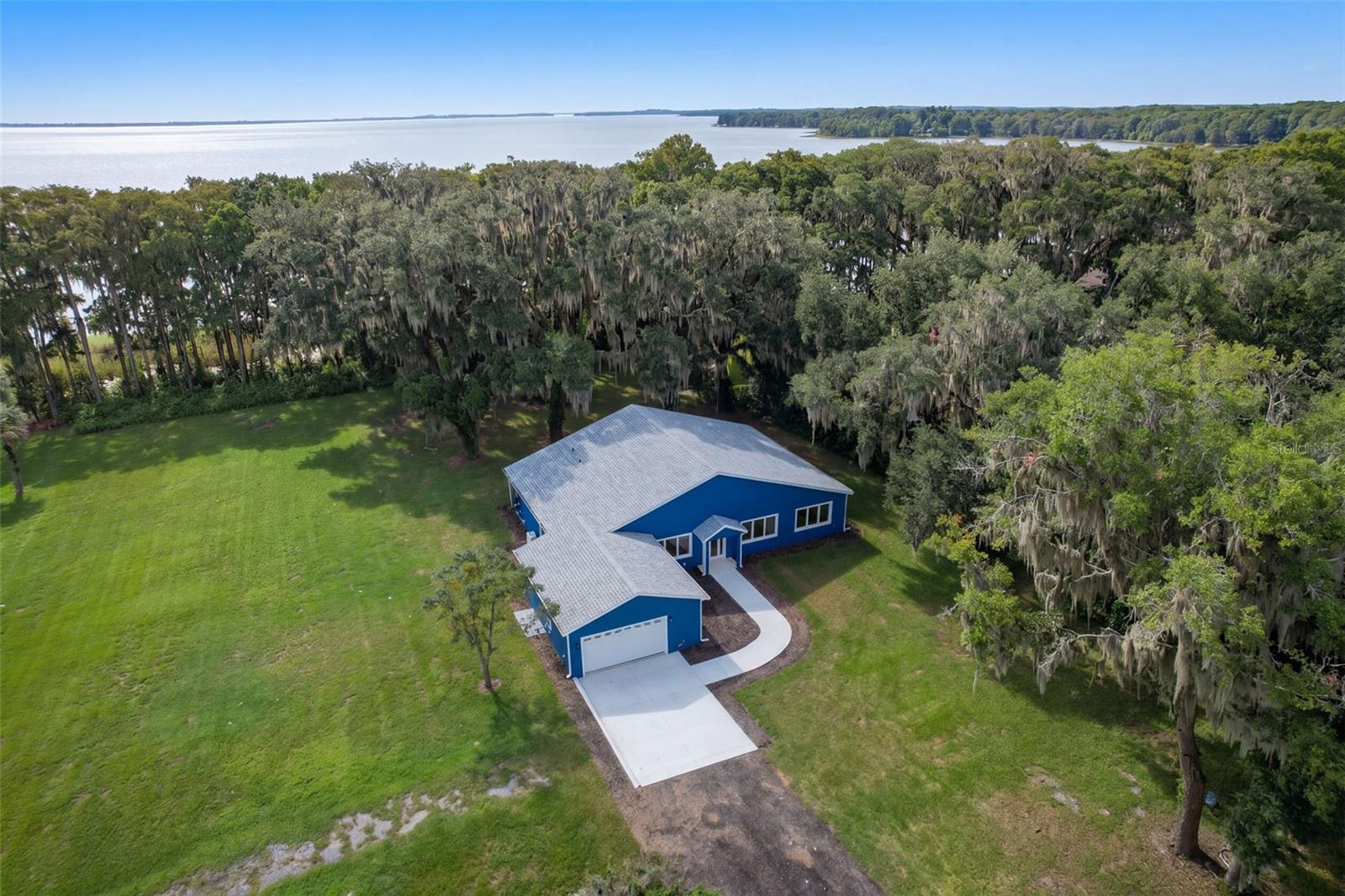 Custom built in 2025 on 1.22 acres with 115 feet of frontage on Lake Harris, part of the Harris Chain of Lakes, 4410 Corley Island Rd is the rare like-new lakefront home where the work is already done. No HOA. No CDD. No 40-year-old roof, plumbing, or AC to replace. Just solid block-and-stucco construction, giant moss-draped live oaks, and open water out back. Best of all, the home itself sits in Flood Zone X.Walk in and the vaulted great room opens up in front of you, with clerestory windows, tall windows, and French doors pulling in natural light and lake views. The kitchen is made for cooking and gathering: navy shaker cabinets with soft-close doors and drawers, butcher block counters, a U-shaped layout with breakfast bar, walk-in pantry, stainless chimney hood, and a 5-burner propane range. The oversized triple window over the sink looks through the porch, past the oaks, to Lake Harris. Doing dishes has never had a better view.The split floor plan gives the primary suite its own side of the home. French doors open straight onto the screened porch, so morning coffee is steps from bed. The en suite bath features dual sinks, a large glass-enclosed walk-in shower, a private water closet, and a linen closet, plus two closets in the suite, including a walk-in. On the other side, two more bedrooms (the second also opens to the porch) share a full bath with a glass walk-in shower. A 14x13 office/den with a triple window overlooking the oaks works as a home office, gym, or 4th bedroom. You also get a half bath for guests, a separate dining room, an indoor laundry room, luxury vinyl plank flooring throughout, and accessibility features already in place, including grab bars, pocket doors, and single-story living with no interior steps.Then step outside. The 66x10 screened porch runs the full length of the back of the home, with ceiling fans and room to dine, lounge, and entertain year-round. Beyond it, the yard rolls toward the water beneath stunning live oaks. With 115 feet of frontage, there is room to plan your own dock, boat lift, or waterfront fire pit (buyer to verify permitting). The Harris Chain connects nine lakes for boating, fishing, and cruising to waterfront towns and restaurants, including Mount Dora by way of the Dora Canal.The details buyers want: 2-car attached garage (26x24), private well, septic, propane, central air, shingle roof, and 2025 construction. No HOA means no one telling you what you can park, plant, or build. 2025 taxes were $3,669 (non-homestead). Cash, conventional, FHA, and VA financing considered.Tucked away on Corley Island Rd, you are minutes from downtown Leesburg, Venetian Gardens, shopping, and dining, with an easy drive to The Villages, Mount Dora, and Florida's Turnpike for Orlando.Lakefront homes on the Harris Chain with this much frontage, this much land, and this new a build rarely come up, and they do not sit long. The home is vacant and easy to show. Schedule your private showing today and see the view from the porch for yourself before someone else calls it home.
