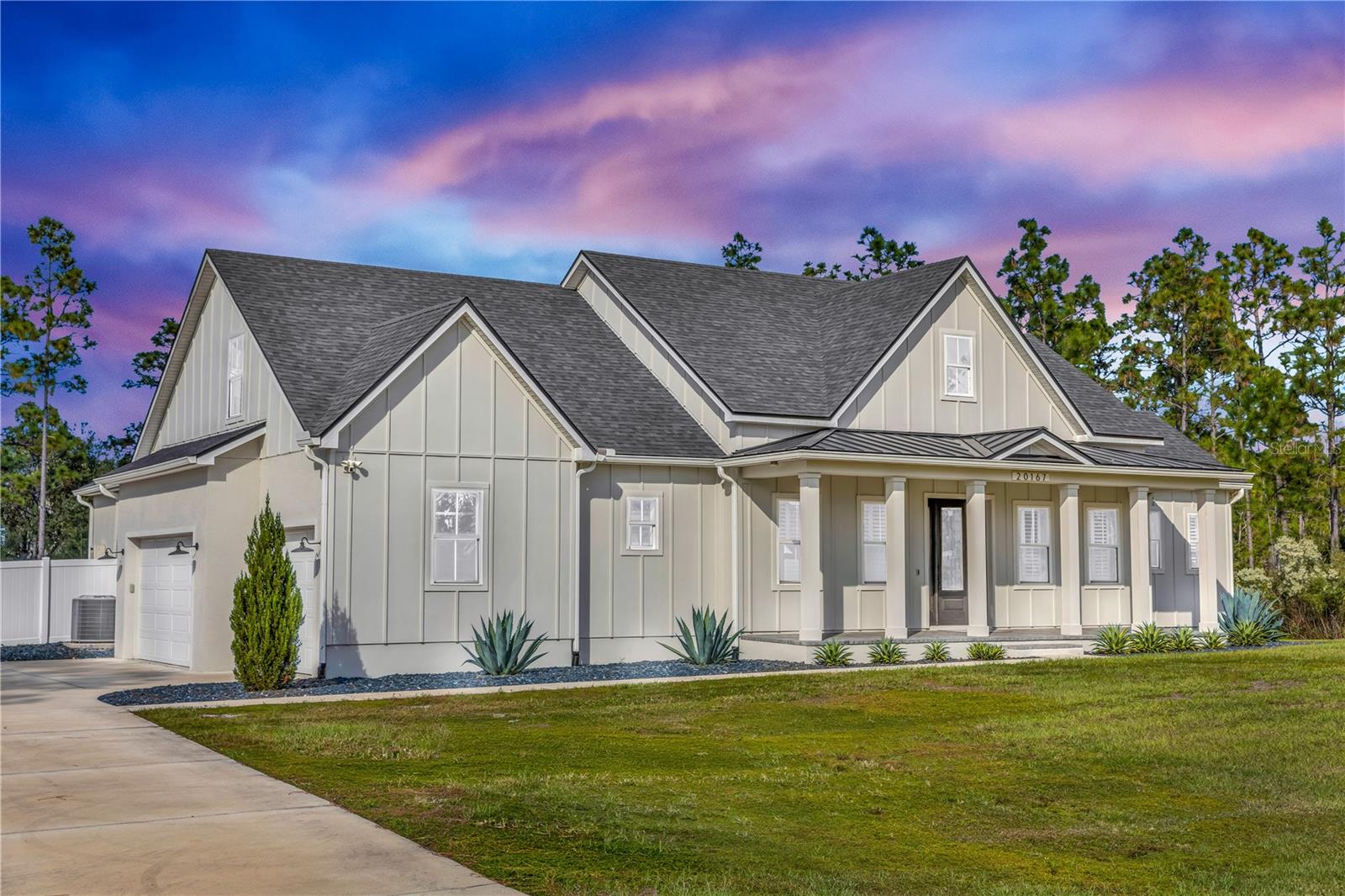 Experience elevated country luxury in this breathtaking custom farmhouse set on 1.24 acres of meticulously manicured grounds, where every detail has been thoughtfully curated for beauty, comfort, and refined living. A stately front patio framed by architectural columns and elegant pavers welcomes you, surrounded by lush, vibrant landscaping that immediately sets a serene tone. Step through the striking faux-wood front door into an entryway that highlights the home’s exceptional craftsmanship and warm design. To the left, a custom-built office features rich cabinetry, glass French doors, and abundant lighting, creating an inspiring workspace with timeless appeal. To the right, a stylish half bath and a coat closet add comfort and convenience. The open-concept living area flows effortlessly into a designer kitchen showcasing quartz countertops, exquisite raised-panel cabinetry, a handcrafted range hood, marble backsplash detailing, and high-end built-in KitchenAid appliances. An oversized walk-in pantry and charming built-in dinette elevate daily living with a blend of elegance and thoughtful functionality. The split floor plan offers outstanding privacy with two spacious downstairs bedrooms, each featuring its own full en-suite bathroom, including one with direct pool access that makes it ideal for guests or flexible living arrangements. The expansive laundry room provides ample cabinetry, a utility sink, and included washer and dryer. Upstairs, a generous loft  and  a fourth bedroom complete with a full bathroom, walk-in shower, and large attic storage. The primary suite is a true retreat, offering French doors that open gracefully to the pool patio and a spa-inspired bathroom with dual vanities, a freestanding soaking tub, a luxurious walk-in shower, and an oversized custom closet designed to impress. Step outside into your private resort-style oasis where the screened-in lanai features an outdoor fireplace and retractable screens that create the perfect atmosphere for year-round enjoyment. The shimmering pool and integrated spa invite relaxation, while just beyond the enclosure a dedicated fire pit area offers a charming setting for quiet evenings beneath the stars. The fully fenced yard blends both vinyl and metal fencing and provides abundant space for boats, RVs, and outdoor recreation. Additional features include an outdoor shower and a whole-home generator ensuring comfort and peace of mind. With a spacious three-car garage, pristine landscaping, and a captivating blend of timeless farmhouse charm and modern luxury, this extraordinary property delivers an exceptional lifestyle that feels serene and truly one of a kind.
