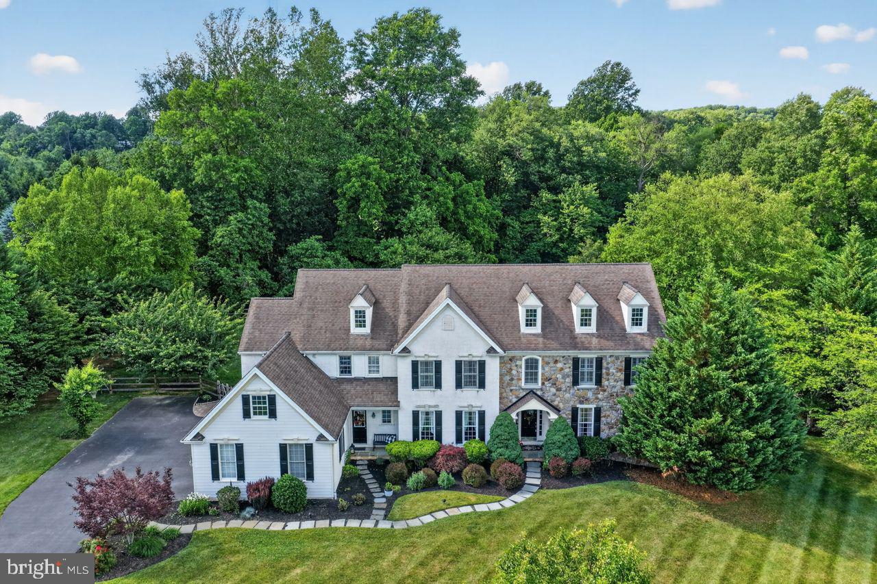 Chantilly Farm — a private enclave of just 34 custom homes in the heart of Chester Springs. This Moser-built residence offers the privacy and scale buyers in this market spend years searching for, anchored by a three-year-old Anthony Sylvan saltwater pool and a sweeping stamped concrete patio.Enter into a two-story foyer where a sweeping staircase makes an immediate impression. The formal living room and formal dining room are built for holiday gatherings and milestone celebrations. At the heart of the home, a gourmet kitchen centers on a massive granite center island with off-white cabinetry. It opens into a vaulted family room with exposed wood beams and a floor-to-ceiling brick fireplace — the kind of space that naturally becomes the center of daily life. A first-floor study offers a quiet retreat for focused work or reading. Two powder rooms and a large mudroom with garage access complete the main level.Sliding doors open to the stamped concrete patio and the Anthony Sylvan saltwater pool, set against exceptional privacy and lush, rolling surroundings. Imagine summer evenings here.Upstairs, the primary suite is a true retreat, featuring plantation shutters, a dressing area, a custom built-in closet, and a spa-inspired bath with a soaking tub, oversized shower, and dual vanities. A second en-suite bedroom, two additional bedrooms sharing a Jack-and-Jill bath, a fifth bedroom, and a large laundry room complete the upper level.The finished lower level raises the bar further. A custom wet bar centers a spacious lounge made for Eagles Sundays and Phillies playoff runs. A dedicated wine storage room adds a finishing touch that collectors and entertainers will immediately appreciate. A powder room adds convenience for entertaining, and a flexible bonus room serves equally well as a home gym, studio, or second study.  Bilco door pool access opens directly to the backyard, and a sizable unfinished area provides abundant storage.The four-car garage features epoxy flooring and handles vehicles, outdoor gear, and more without blinking. Additional highlights include a recently updated HVAC system and a newer hot water heater — the hallmarks of a home maintained with genuine care. The HOA includes annual septic inspections, simplifying routine maintenance.Set within the award-winning Downingtown Area School District, home to the nationally recognized STEM Academy, with easy access to the Montgomery School, the PA Turnpike, Route 30, Route 202, Marsh Creek State Park, Bryn Coed Preserve, and the rolling open spaces Chester Springs is known for.1704 Chantilly Lane delivers 5 bedrooms, 3 full baths and 3 half baths, approximately 4,910 sq ft above grade plus an estimated 1,500+ sq ft of finished living space below grade (buyer to verify). The beauty and privacy of this property must be experienced in person — schedule your private tour today.