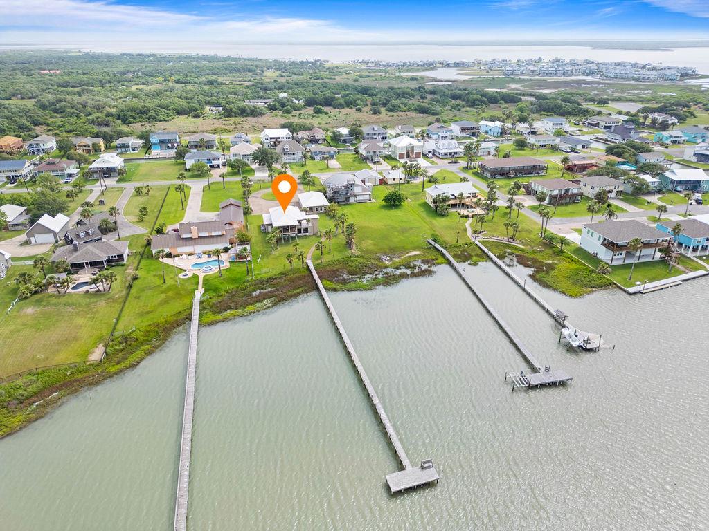 Bayfront living inside and out—your dream coastal retreat on beautiful St. Charles Bay. This bayfront gem offers breathtaking views, a private fishing pier, and nearly an acre of peaceful waterfront living. All bedrooms are conveniently located on the ground floor, creating easy access and a comfortable layout. Upstairs, you'll find a spacious open-concept living, kitchen, and entertaining area with walls of windows to soak in the stunning views. Step out onto the expansive upper deck for relaxing, dining, or enjoying coastal breezes. An elevator adds extra convenience between levels. Perfect for hosting, the detached guest house features its own private entrance, giving visitors space and privacy. The massive detached garage easily fits boats, cars, and includes room for a workshop or storage. Topped with a durable metal roof and designed for both function and fun, this property is a rare find on the Texas coast—ideal as a primary home, vacation getaway, or investment. Don't miss your chance to own a slice of bayfront paradise!