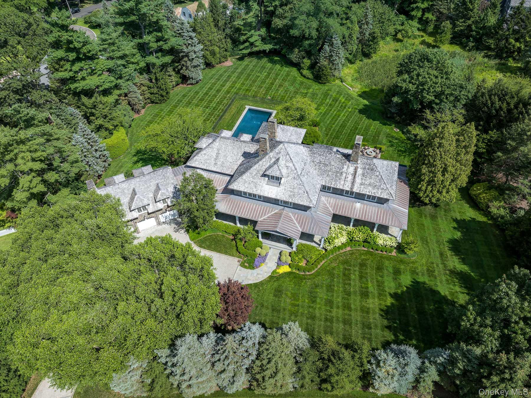 Nestled privately, and surrounded by matured trees, on 1.82 bucolic mid-country acres, sits this seven bedroom, seven full and three half bath, gorgeous estate! Extraordinary stone & shingle construction, built by Aberdeen Properties, and gardens magnificently designed by Rutherford & Associates. Dramatic front to back, double height entry, exquisite millwork throughout, 10’ ceilings, and a comfortable open flow. Ideal for both everyday living and grand scale entertaining! Fabulous primary suite, with sitting area, plus five other spacious ensuite bedrooms, and a separate guest suite. Gourmet kitchen with sun-filled breakfast area and large pantry, formal dining room, family room, living room and magnificent office/library that is privately located at the end of the first floor. Finished lower level with gym/extra ensuite bedroom, another family/hang out room, home theater & spectacular wine room. Outside is a private, resort like oasis, with a large flagstone patio, fire pit, pizza oven, jacuzzi and a magnificent pool, overlooking the gorgeous manicured lawn! Minutes to shops, five-star restaurants, beaches, parks, train and major highways for an easy commute to NYC. Luxury, comfort, privacy and convenience…this one has it all!