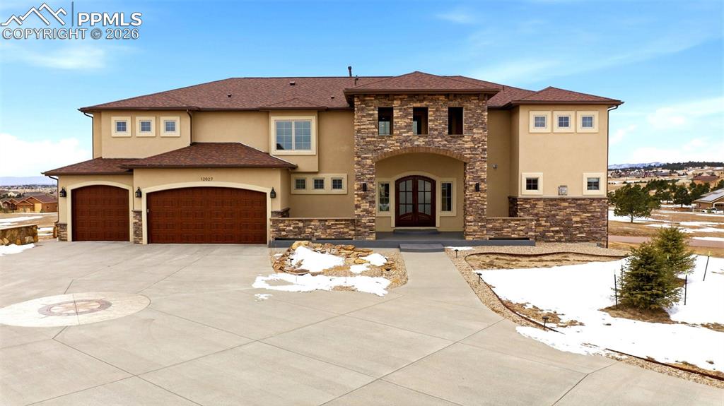 Perched atop 2.5 acres overlooking the highest point in Antlers Ridge, this custom-built residence blends luxury, comfort, and Colorado’s most captivating vistas. Step inside to a main level crafted for entertaining: a gourmet kitchen anchors the open layout, flowing effortlessly into a grand great room with soaring ceilings and a statement fireplace scaled to the room’s dramatic volume. The dining area opens to a covered patio framing panoramic views from Pikes Peak to the Wet Mountains and the Sangre de Cristos—perfect for sunset gatherings around the fire pit and sparkling city lights after dark.Five oversized bedrooms each feature an en-suite bath and walk-in closet. Custom tilework shines throughout—from live-edge travertine floors to bespoke bath designs. A wet bar and game room on the main level delivers show-stopping ambiance with a fiber-optic “starlit sky” ceiling installed by a lighting engineer from Disney Cruise Lines; light the fireplace and savor a cinematic experience without leaving home.The primary suite pampers with heated bathroom floors and dual walk-in closets. Everyday ease comes from a main-level office with custom built-ins, upstairs laundry, whole house central vac, a walk-in pantry, three fireplaces, two central AC units plus a dedicated split AC for the primary, and six security cameras. Car enthusiasts will appreciate garage capacity for up to 11 cars—or 9 plus a full-size RV—along with an upstairs workshop in the detached garage and low-maintenance landscaping. The newly finished walkout basement extends your lifestyle with a large rec room, workout room, safe room, and abundant storage.