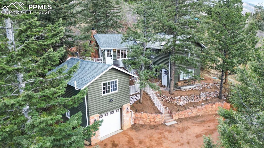 Tucked into the heart of Green Mountain Falls, this extraordinary mountain retreat offers the rare blend of luxury, flexibility, and timeless Colorado charm. Set on over half an acre of beautifully treed grounds with captivating views, dramatic rock outcroppings, and exceptional privacy, this one-of-a-kind property presents three thoughtfully designed living spaces totaling 1,357 square feet, with 3 bedrooms and 3 bathrooms.The main residence exudes warmth and character, featuring rich wood flooring, a beautifully updated kitchen and bath, and a stunning native Colorado flagstone fireplace that anchors the inviting great room. Soaring beamed vaulted ceilings enhance the sense of space and mountain elegance, while large windows frame the serene natural surroundings.The walk-out lower-level apartment has been tastefully renovated and offers its own private entrance, stylish vinyl plank flooring, a tiled ¾ bath, stackable washer and dryer, a comfortable bedroom, and a charming kitchenette with pantry… ideal for guests, multigenerational living, or income potential.Above the detached garage, an additional beautifully finished studio-style unit provides even more versatility, perfect as a guest retreat, creative space, home office, or supplemental rental opportunity.Every detail of this property has been thoughtfully updated, creating a seamless blend of rustic luxury and modern comfort. Spend peaceful summer evenings on the secluded flagstone patio complete with a built-in barbecue, surrounded by towering trees and tranquil mountain beauty. Just moments from hiking trails, the town square, local pond, and boutique shopping, this is a truly rare opportunity to own an exceptional mountain escape in one of Colorado’s most beloved communities.