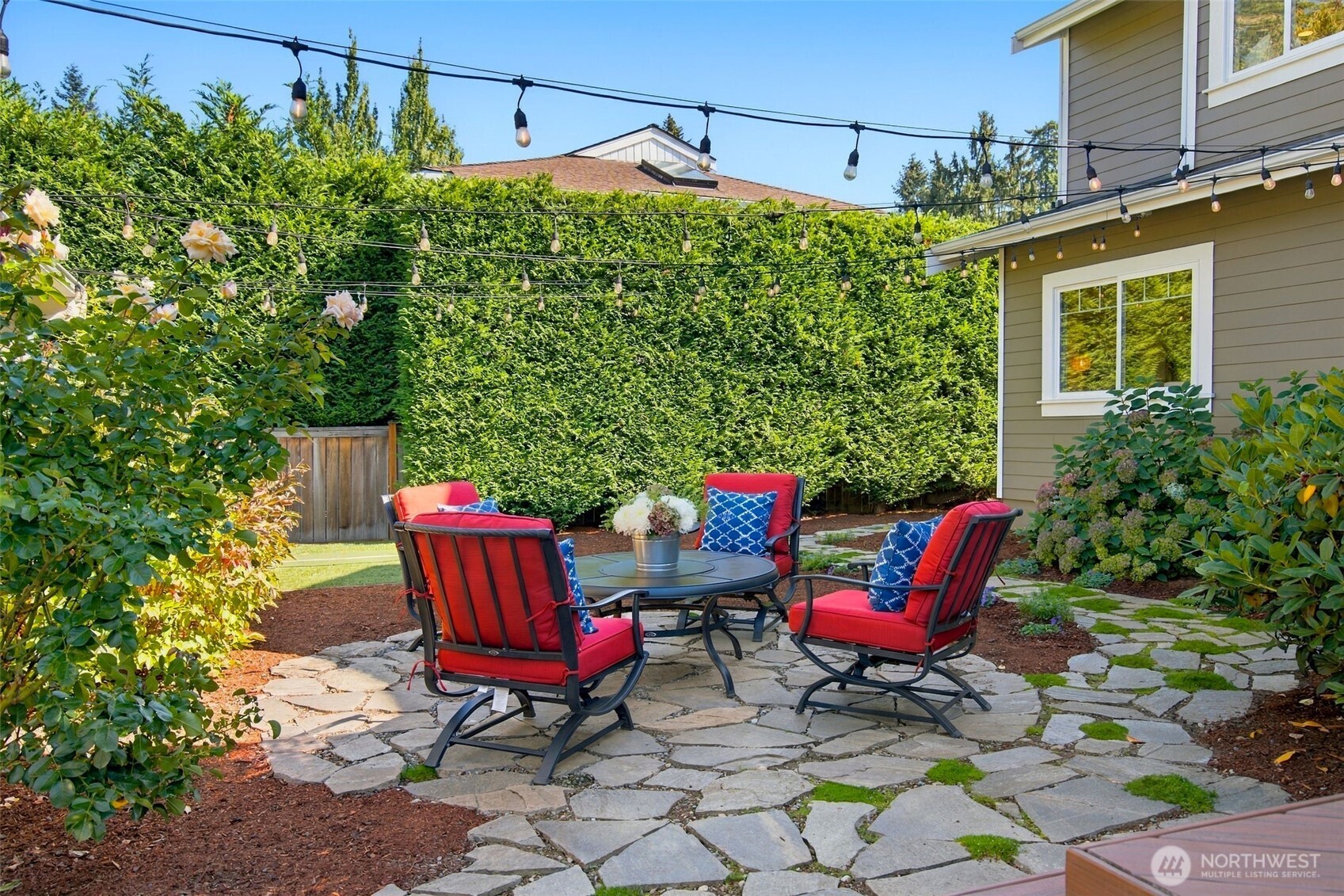 Tall, lush hedges wrap a flagstone patio and fire pit, so outdoor gatherings stay fully private.