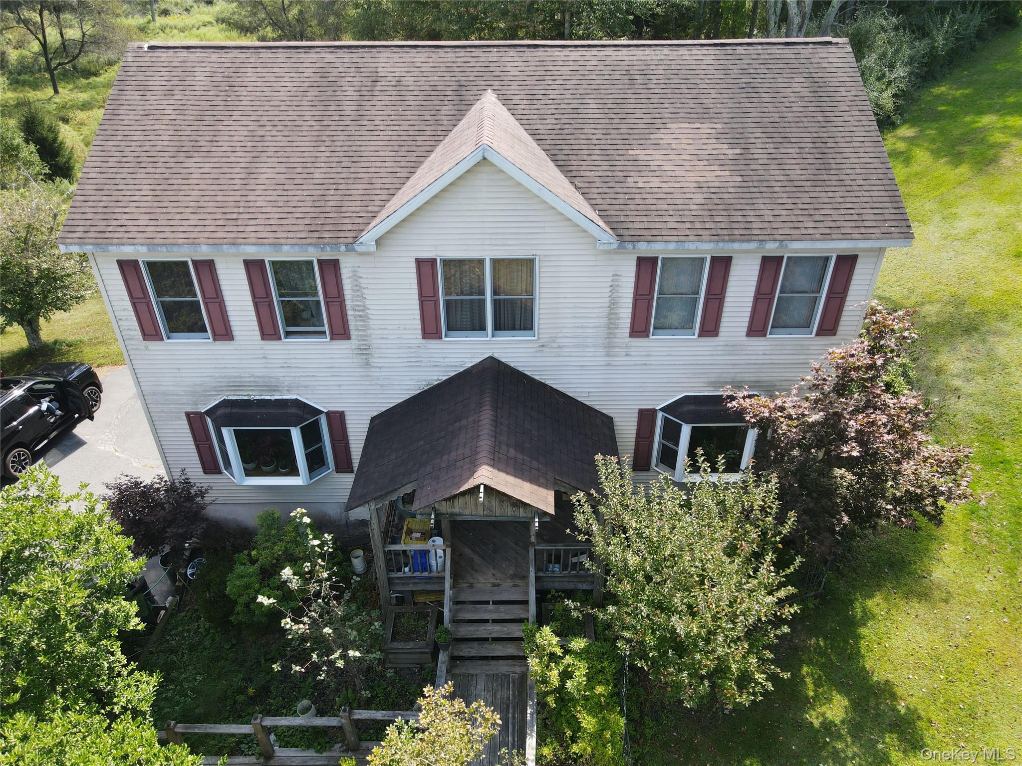 Colonial home with a shingled roof, stairway, and a front lawn