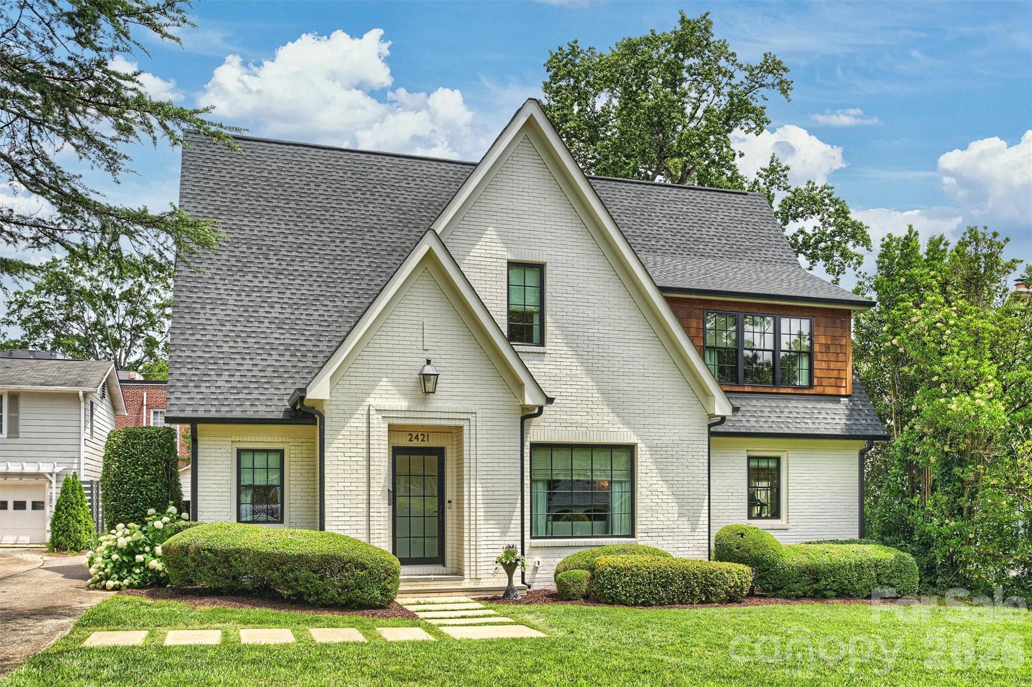 Stunning white painted brick home in Myers Park! A covered bluestone entry and gas lantern create exceptional curb appeal at this beautifully designed home. The expansive living room is anchored by a marble-surround fireplace with gas fire balls and a striking oversized divided-light window that fills the space with natural light. The open dining room adjoins a custom barrel-arched lounge, creating a warm and inviting alcove. Next to the dining area, a bar with beverage fridge and open shelving enhances the entertaining space with glass French doors leading to the back yard. The updated kitchen features quartzite countertops, custom white cabinetry, brass hardware, peninsula bar seating, and premium appliances including a Wolf range. A nicely sized loft offers versatile living space. The primary suite is breathtaking with a vaulted ceiling, exposed wood beams and a dreamy ensuite bathroom: heated black and white tile marble floors, a soaking tub, floating dual vanity, frameless glass shower with full marble surround and two walk-in closets. A secondary vaulted ceiling bedroom and gorgeous green tiled bathroom complete the upper level. The main level includes a third bedroom featuring an updated ensuite bathroom with marble counters, dual vanities and a walk-in shower. A fourth bedroom offers flexibility as a private office or guest room with easy access to a fourth full bathroom . This home is complete with a drop zone finished with built-ins and statement wallpaper transitioning into a large laundry room with abundant cabinetry and storage. Great outdoor living with an expansive rear deck offering both dining and lounge space overlooking the fenced backyard. Just blocks from Selwyn Avenue retail and restaurants. Welcome home!
