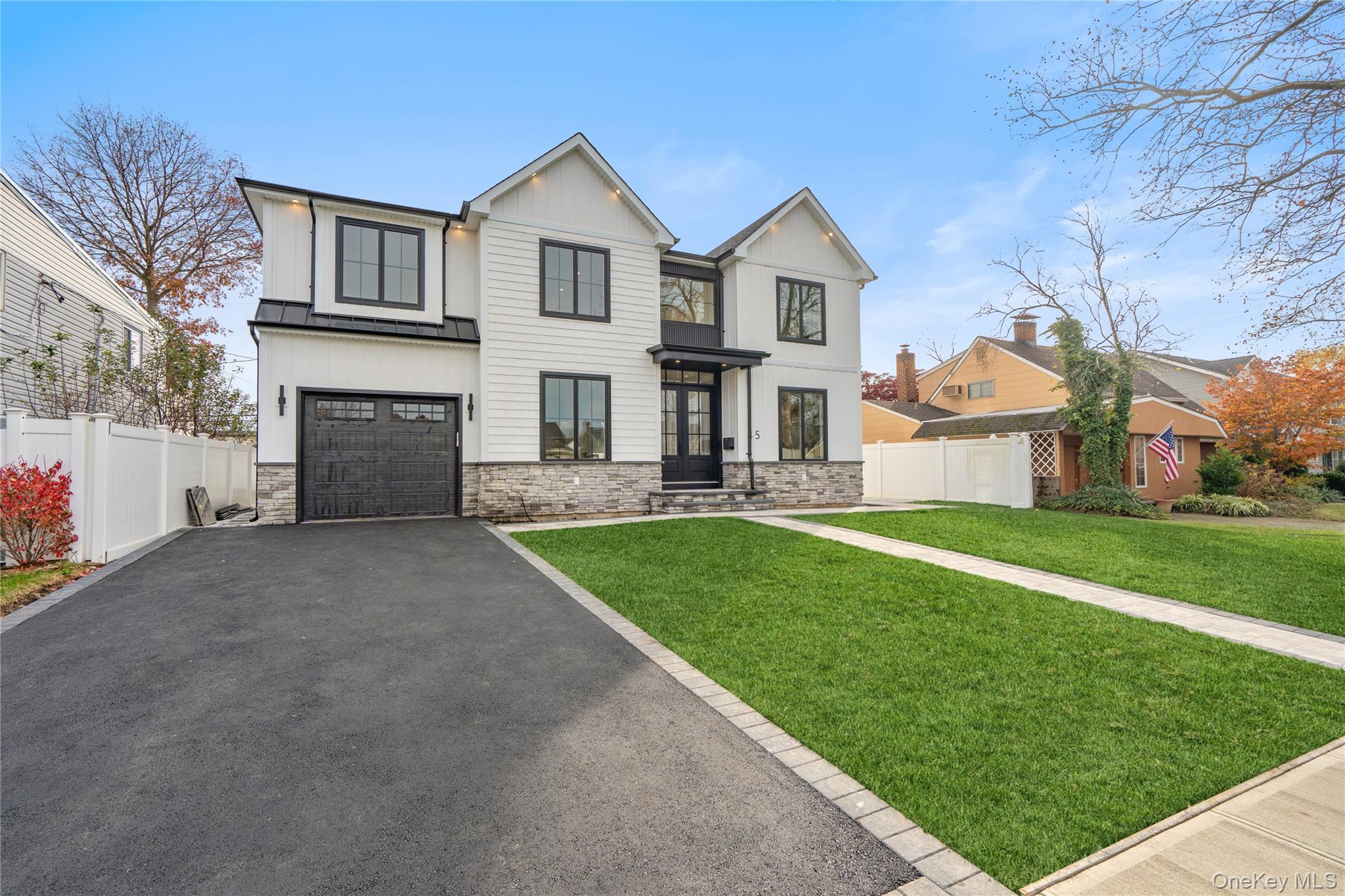 This brand-new construction blends modern farmhouse style with timeless elegance, offering 5 bedrooms, 5.5 baths, and a fully finished basement with outside entrance. The first floor features a dramatic double-height entry with custom raised panel detailing that flows into the formal dining room with built-in hutch, complete with a coffered ceiling and dry bar—perfect for entertaining. Wide-plank white oak hardwood floors, 9-foot ceilings, and custom crown molding create a seamless sense of luxury. A spacious first-floor bedroom or office, full bath, ideal for extended family. The chef’s kitchen boasts gas cooking, an oversized island, premium stainless-steel appliances, and LED accent lighting. The adjoining family room includes a gas fireplace with built-in cabinets on either side,  and sliders leading to a professionally landscaped, fenced yard with paver patio. Second floor features four oversized bedrooms, including a primary suite with decorative ceiling, coffee bar, walk-in closets, and a spa-like bath with soaking tub, glass-enclosed shower, double vanities, plus make-up vanity, and radiant heated floors. A laundry room, and 3 additional bedrooms, two more full bathrooms complete the second level. The fully finished 1,600 sq. ft. basement with a full bath and outside entrance offers endless possibilities—home gym, media room, bar, or more. East Meadow School District